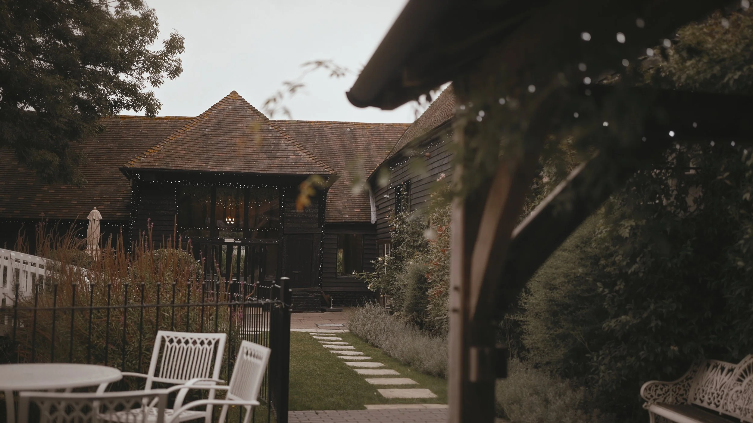 A wide establishing shot from a cinematic wedding film, showing the black exterior of Winters Barns wedding venue.