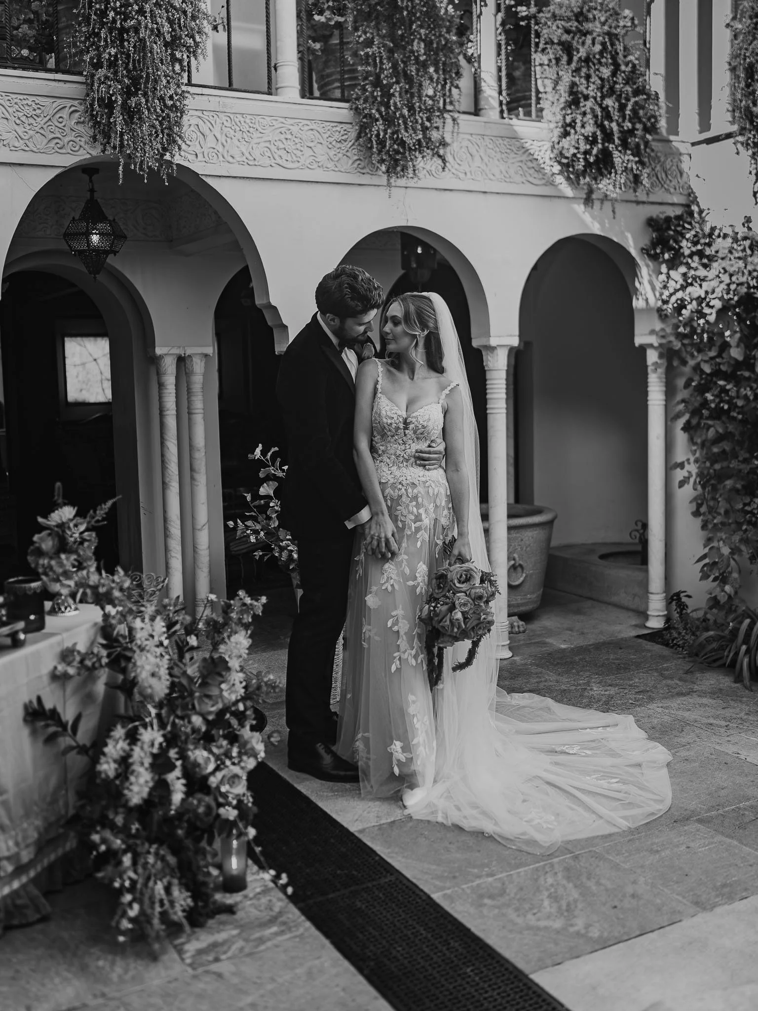 Couple stand in a courtyard during their portrait session, posing for a fine art wedding photography and videography team.