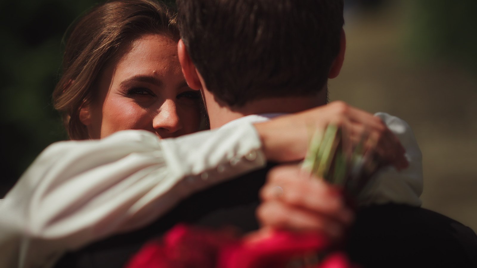 A bride wraps her arms around her groom and stares straight at the camera in an editorial fine art moment in a wedding film.
