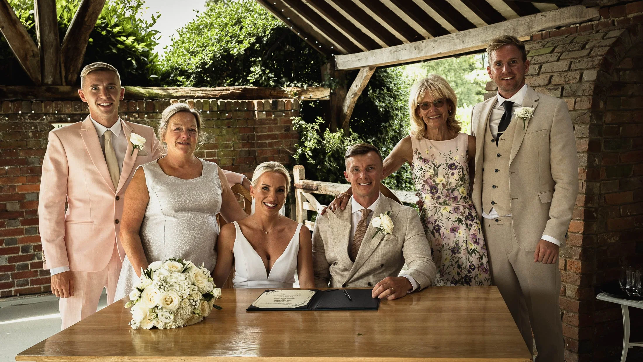 A group portrait of the witnesses and the bride and groom signing the register after the wedding ceremony at Winters Barns.