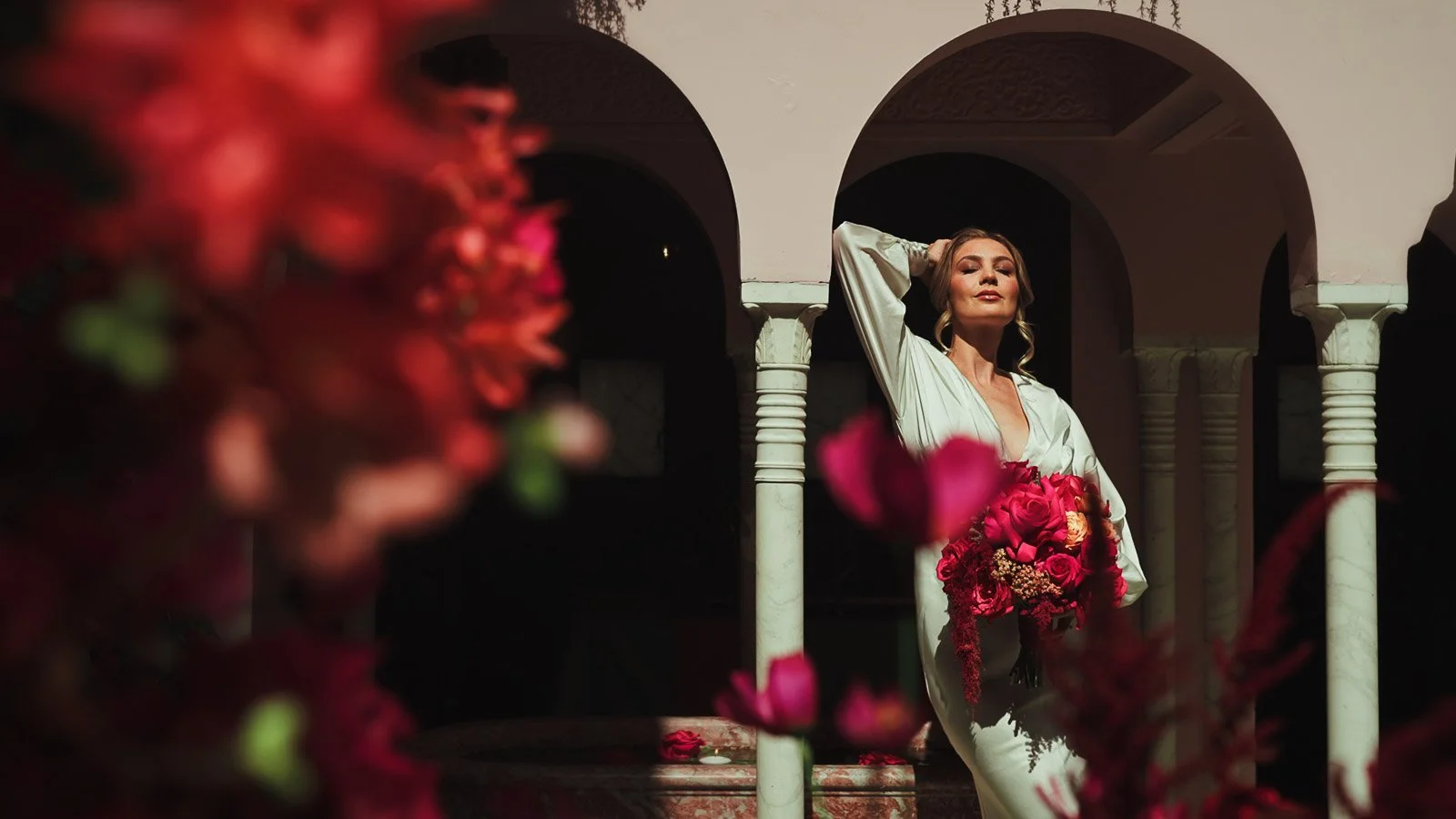 Fashion styling detail shot with a bride and pink and red florals and elegant textures