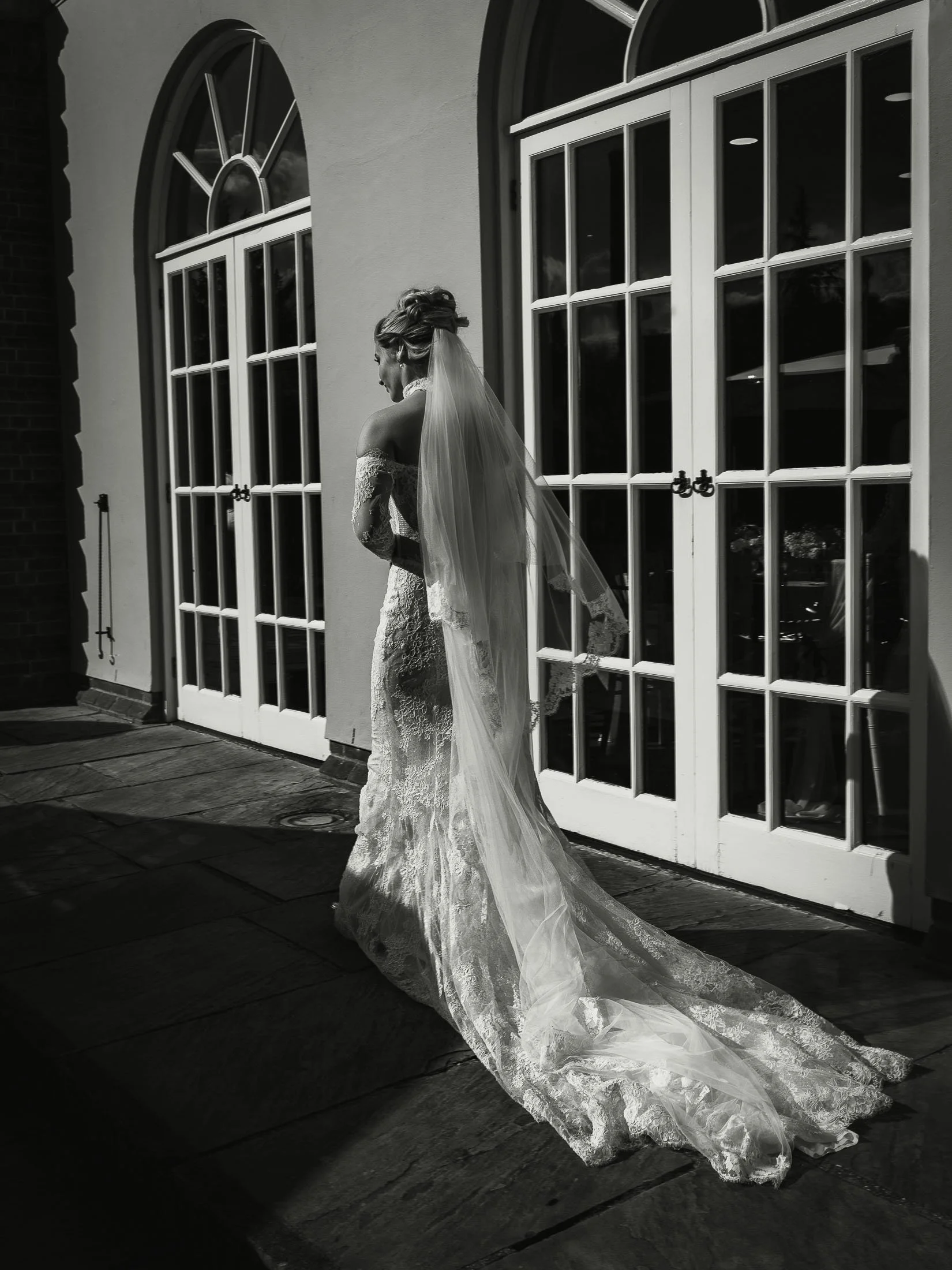 Candid black and white moment captured in an editorial style of a bride walking at The Orangery Maidstone.