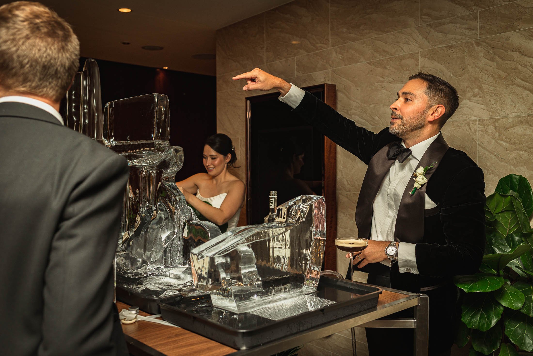 A candid moment as a bride and groom serve their guests shots and drinks during evening celebrations of their black tie London wedding.