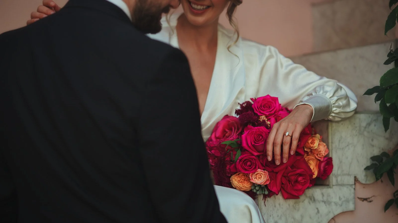 Vivid pink and red florals styled against textured courtyard backdrop