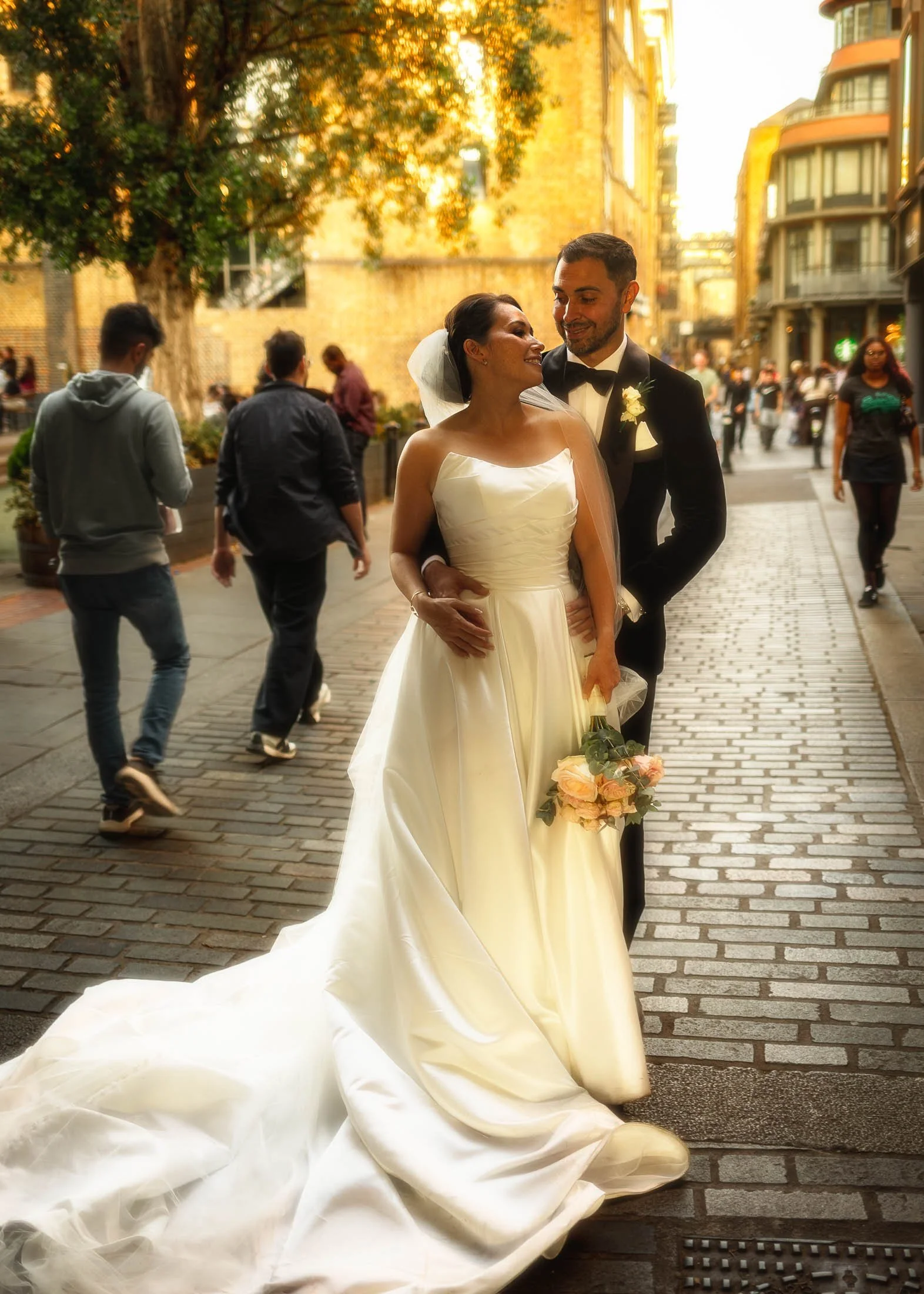 A timeless wedding pose by a bride and groom standing underneath an archway that runs underneath Tower Bridge during their London wedding day.