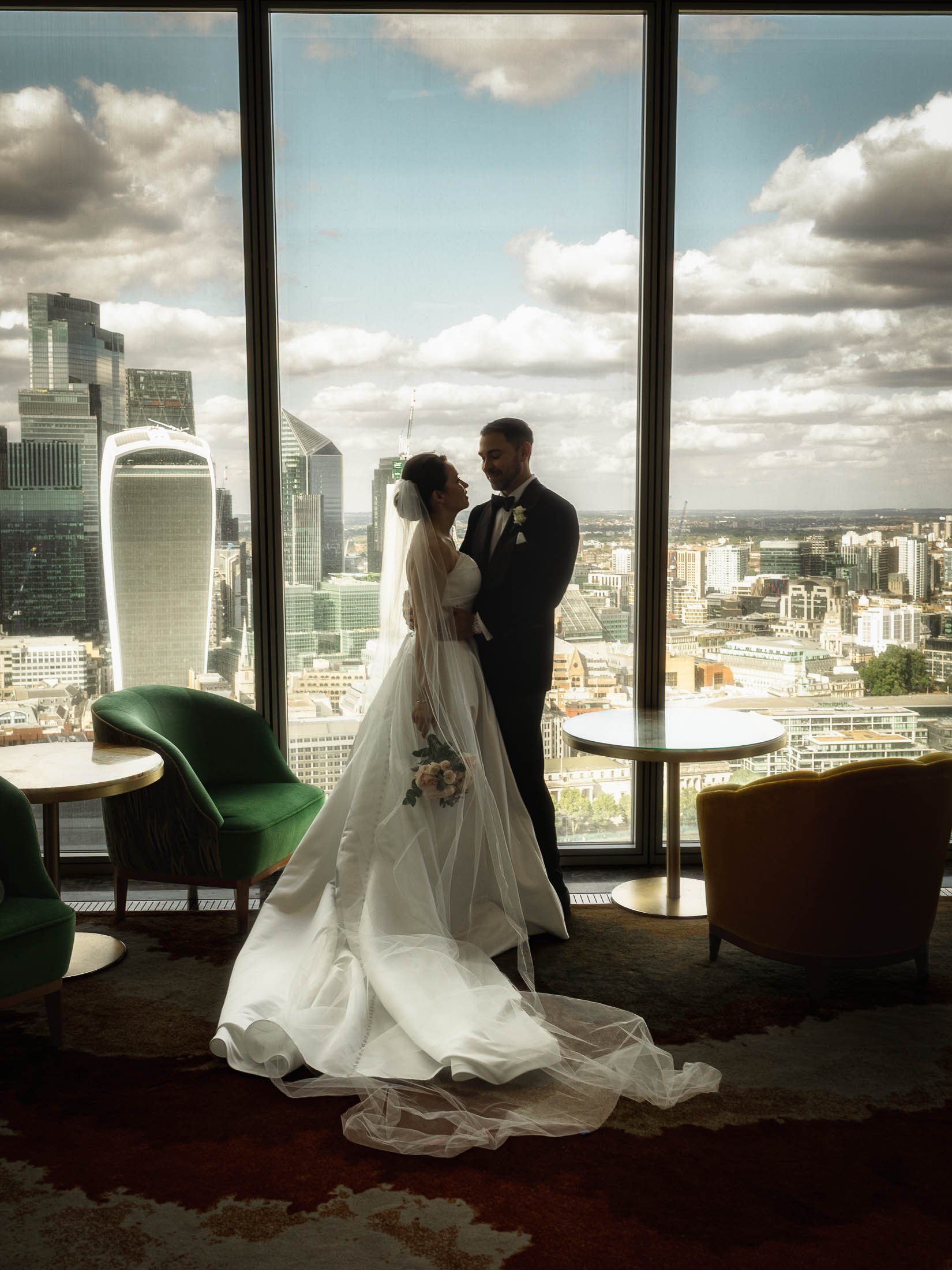 A full length editorial wedding photograph of a couple on the 34th floor of The Shard in London, with the skyline of London city behind them.