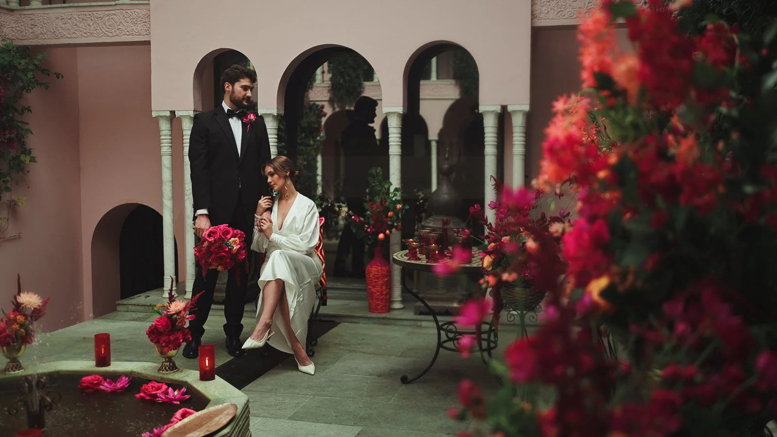 Black-tie couple portrait in a courtyard setting with refined, colourful fine art styling