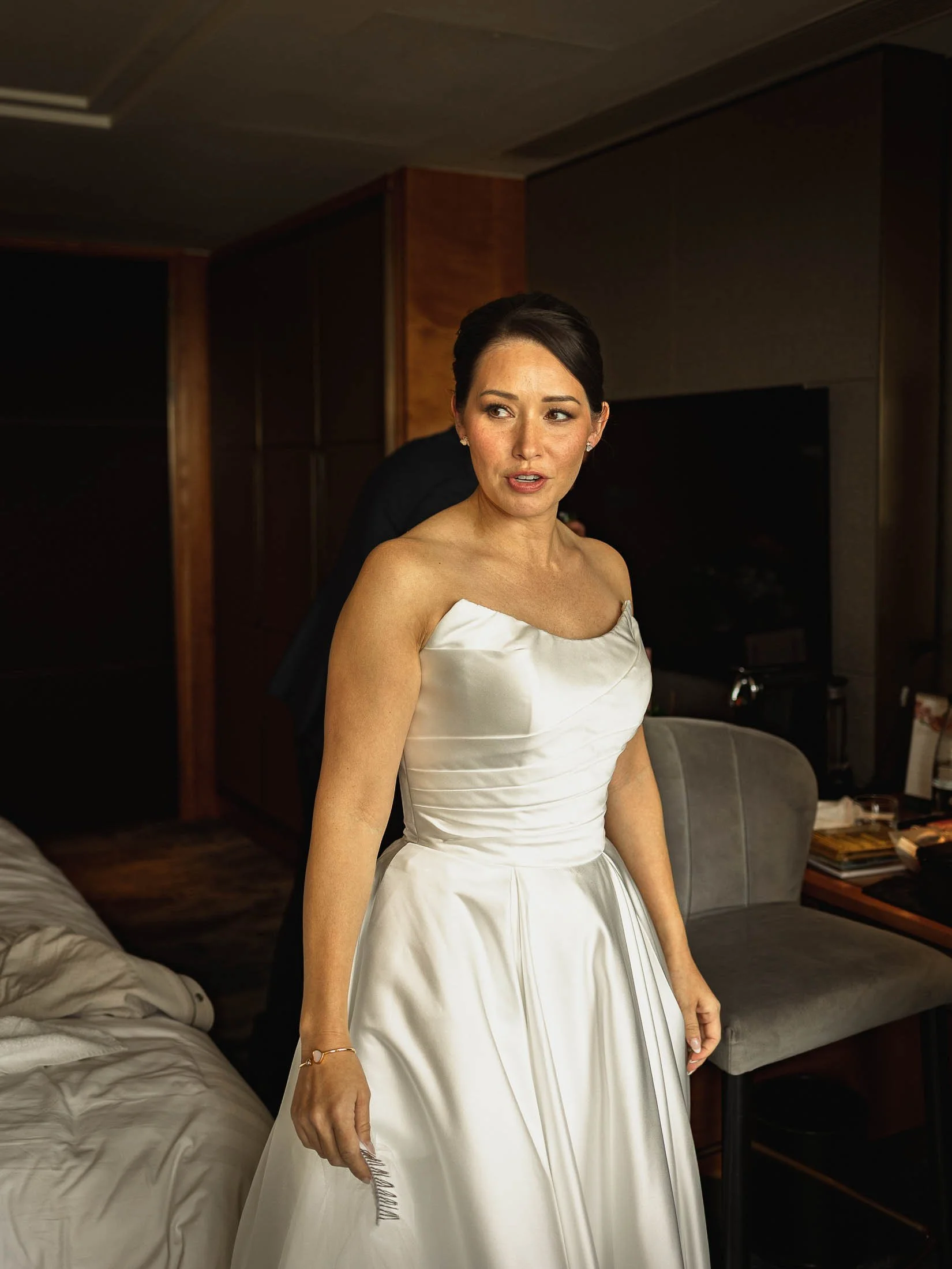 A bride gets into her luxurious wedding dress on the morning of her black tie London wedding at the Shangri-La The Shard.