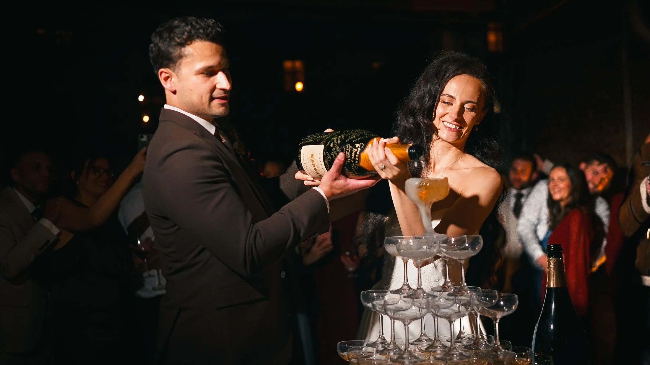 Bride and groom pour Champagne into a tower of glasses at Elmore Court.