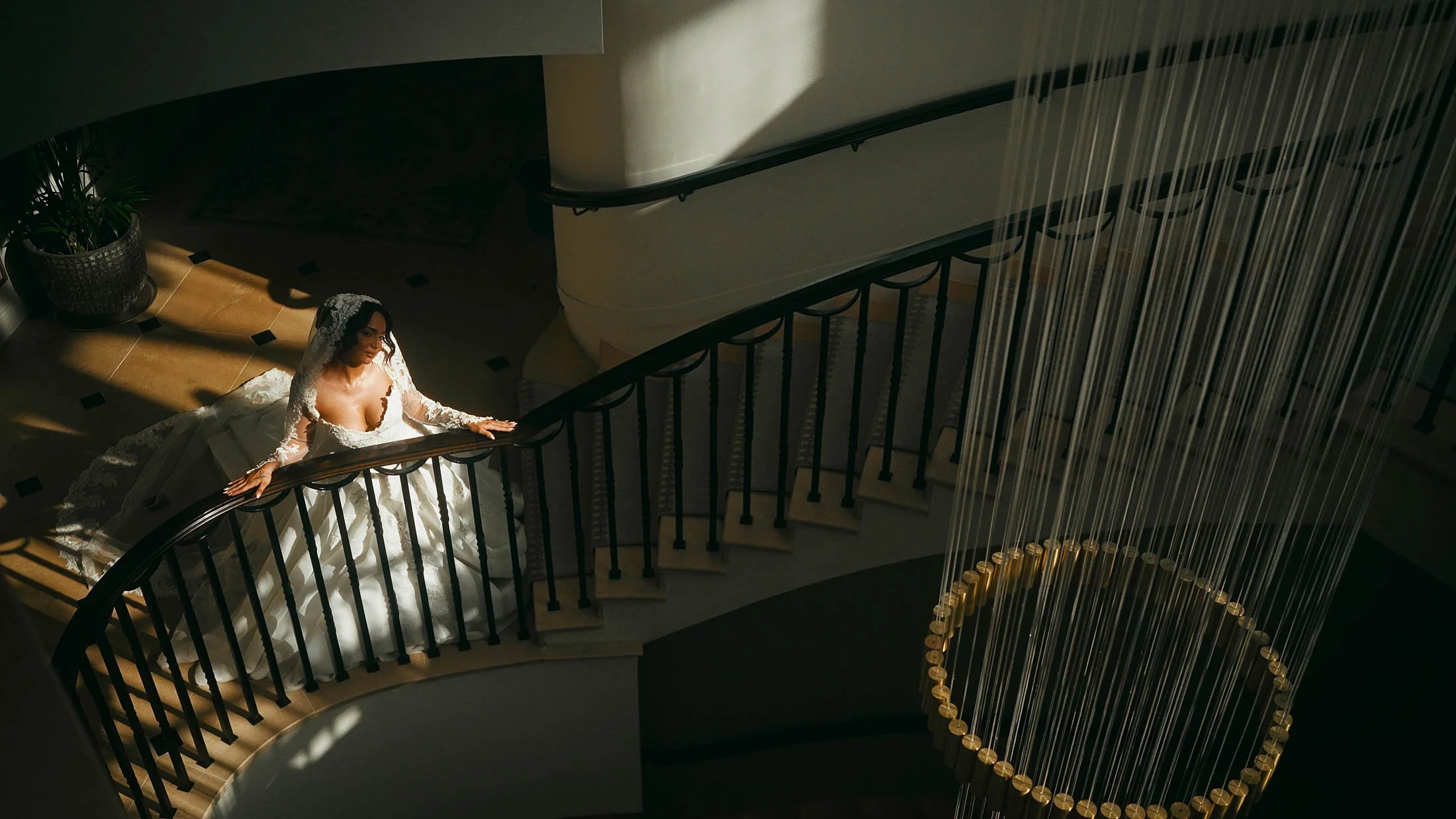 A bride stands at the bottom of the staircase at Grantley Hall for a cinematic wedding videography shot.