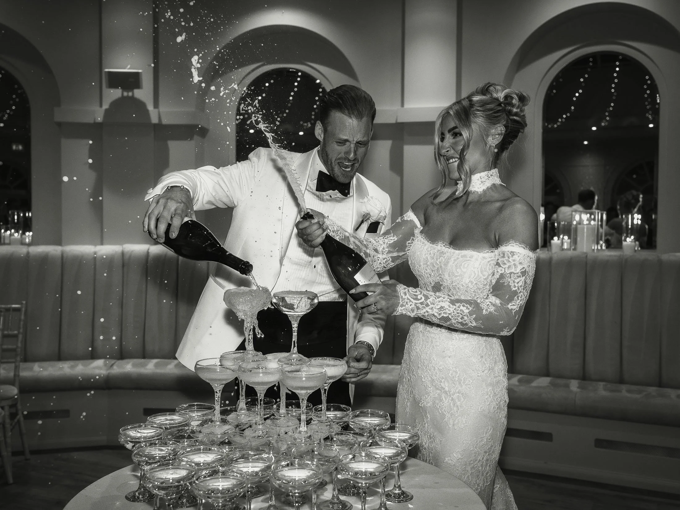 Editorial wedding photography and videography at The Orangery Maidstone as a bride sprays Champagne from the bottle and laughs.