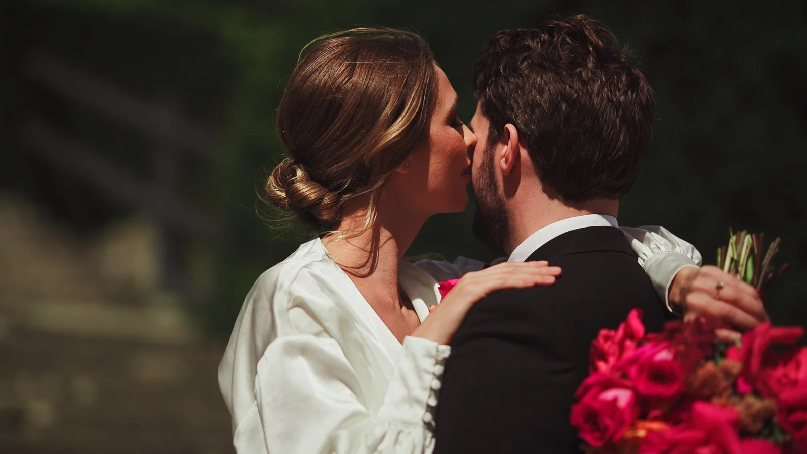 A modern pose for fashion-forward couples during a black tie wedding as the bride whispers in the grooms ear.
