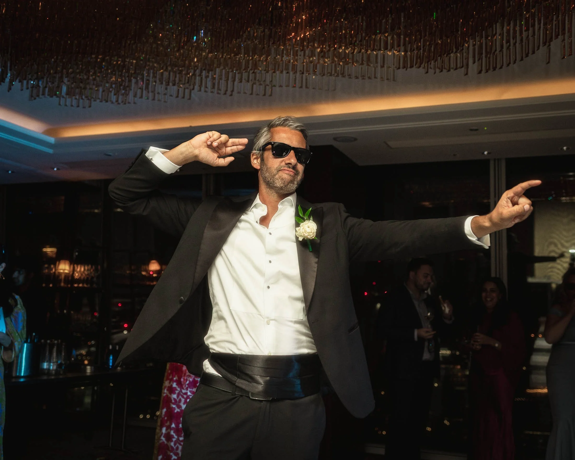 A relaxed black tie portrait of a guest dancing during a London wedding celebration.