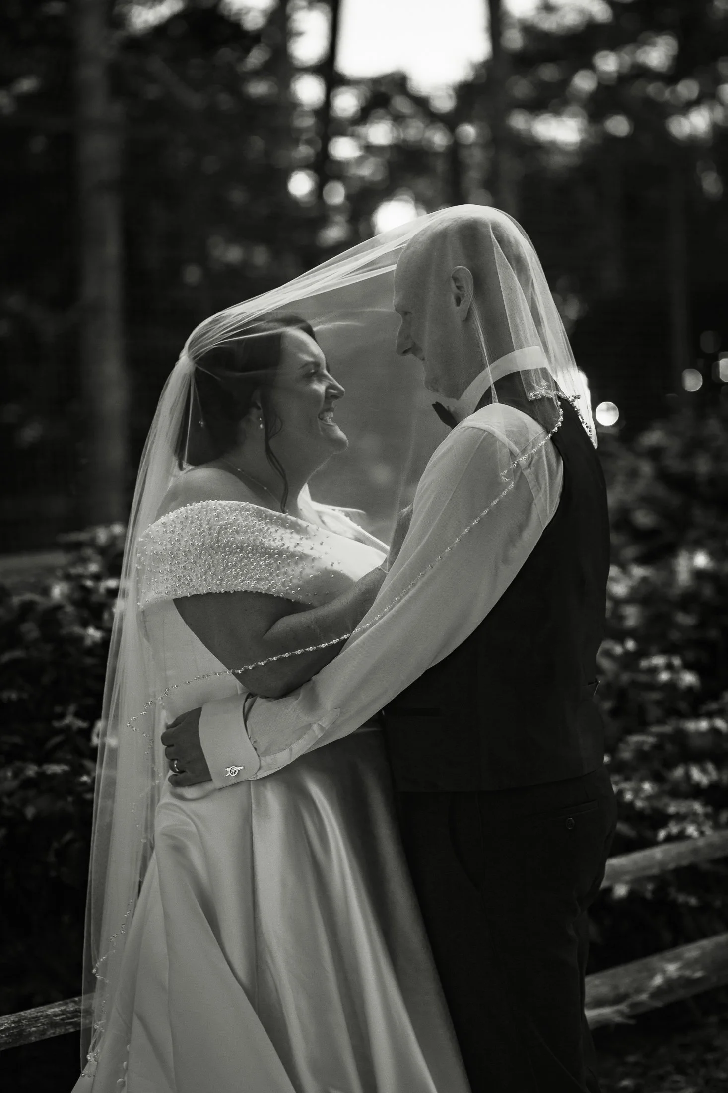 A bride and groom stand underneath a veil at sunset on their Port Lympne wedding day.