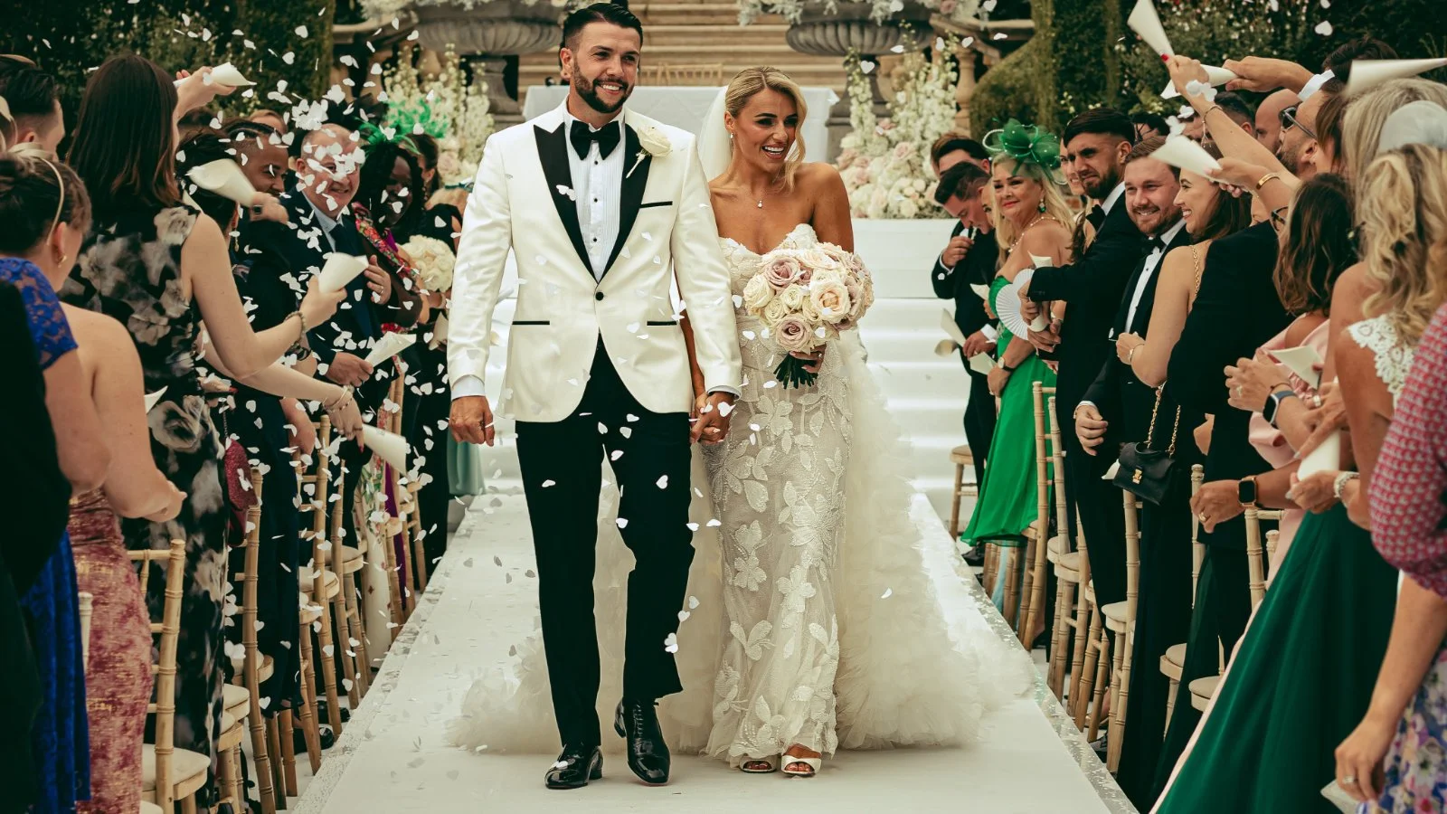 A couple exiting their luxury outdoor wedding ceremony in the UK, captured by Kent wedding videographer and photographer Luke Batchelor Productions.