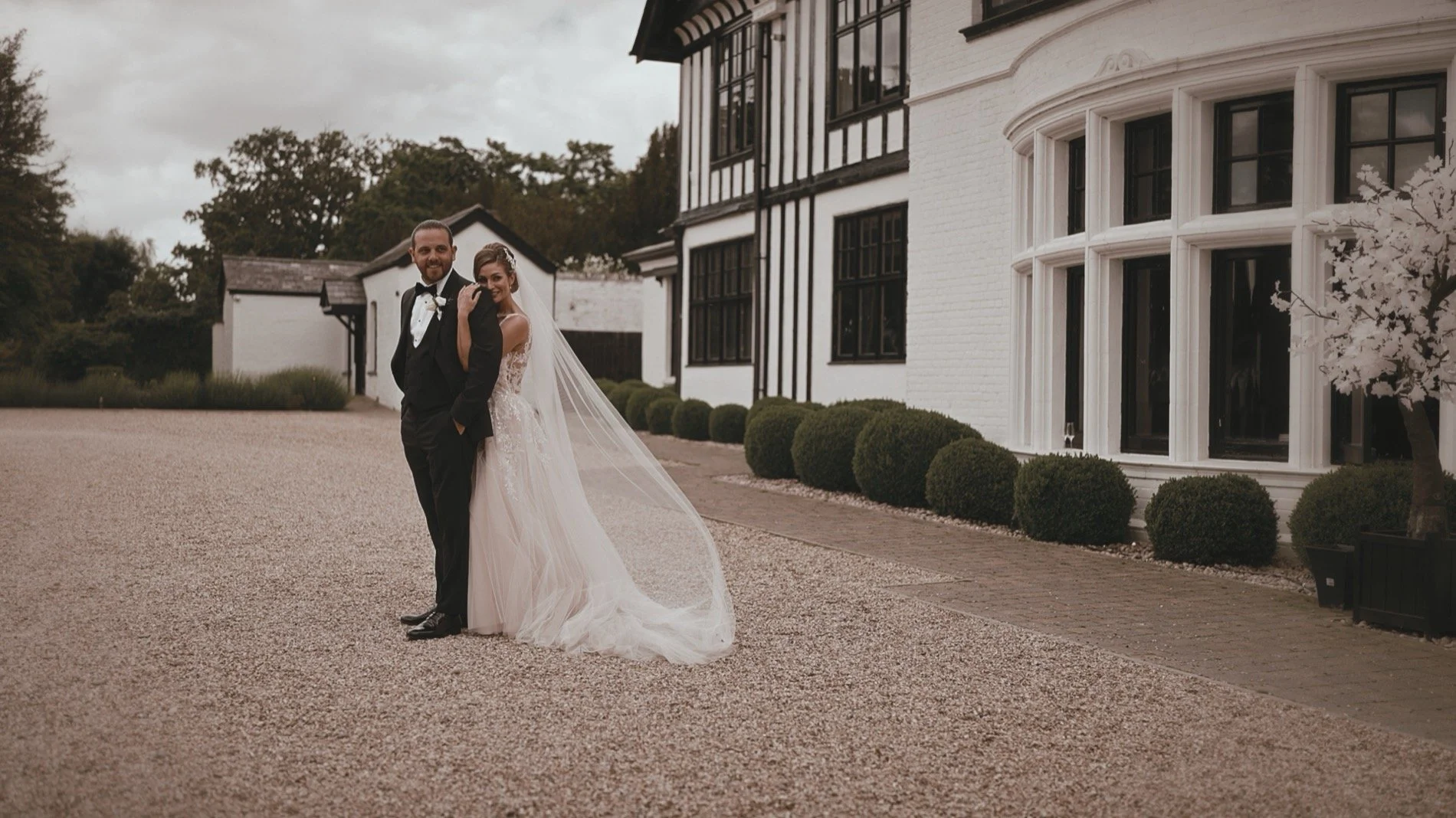 A couple walking through the grounds of Swynford Manor in Suffolk during their black-tie wedding day