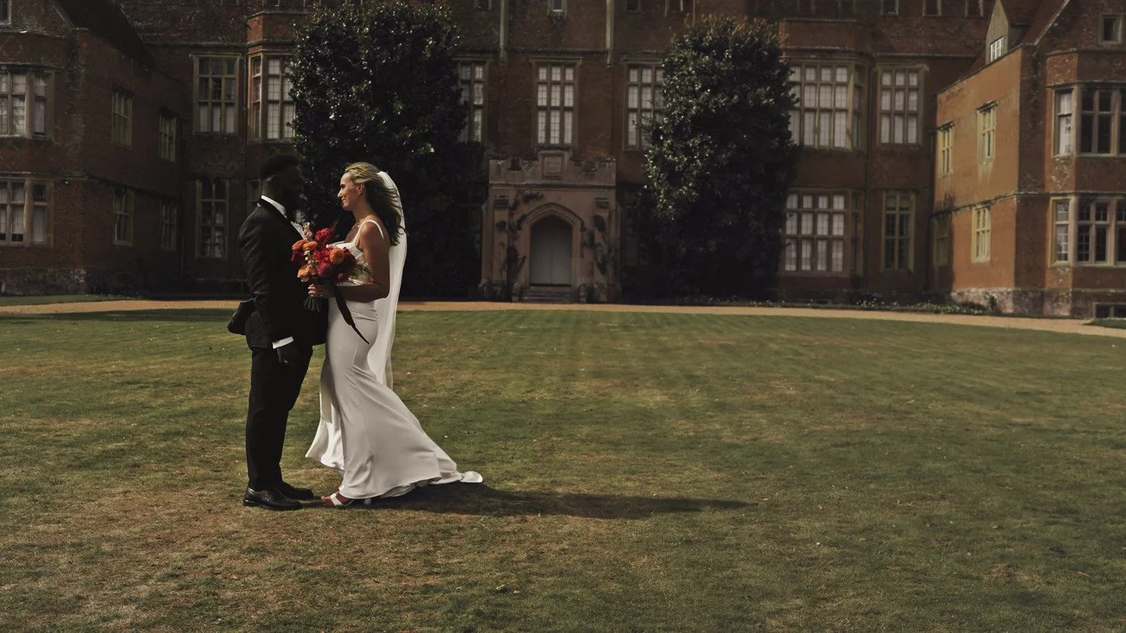 A couple pose together for portraits at sunset on the banks of the River Thames during their Oxfordshire Estate wedding.