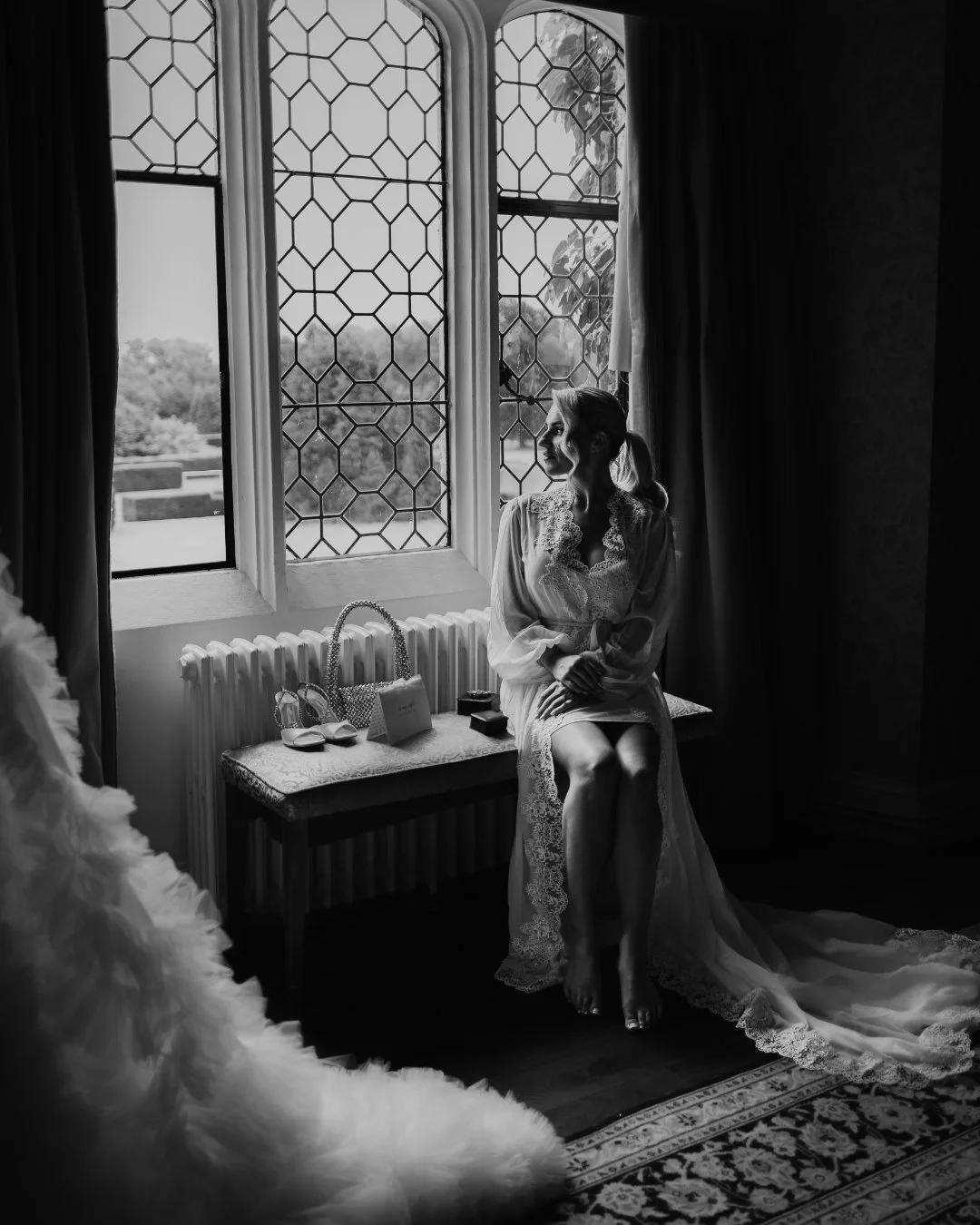 A luxurious black and white bridal portrait by a large window, captured in a cinematic way by Kent wedding videographer Luke Batchelor Productions.