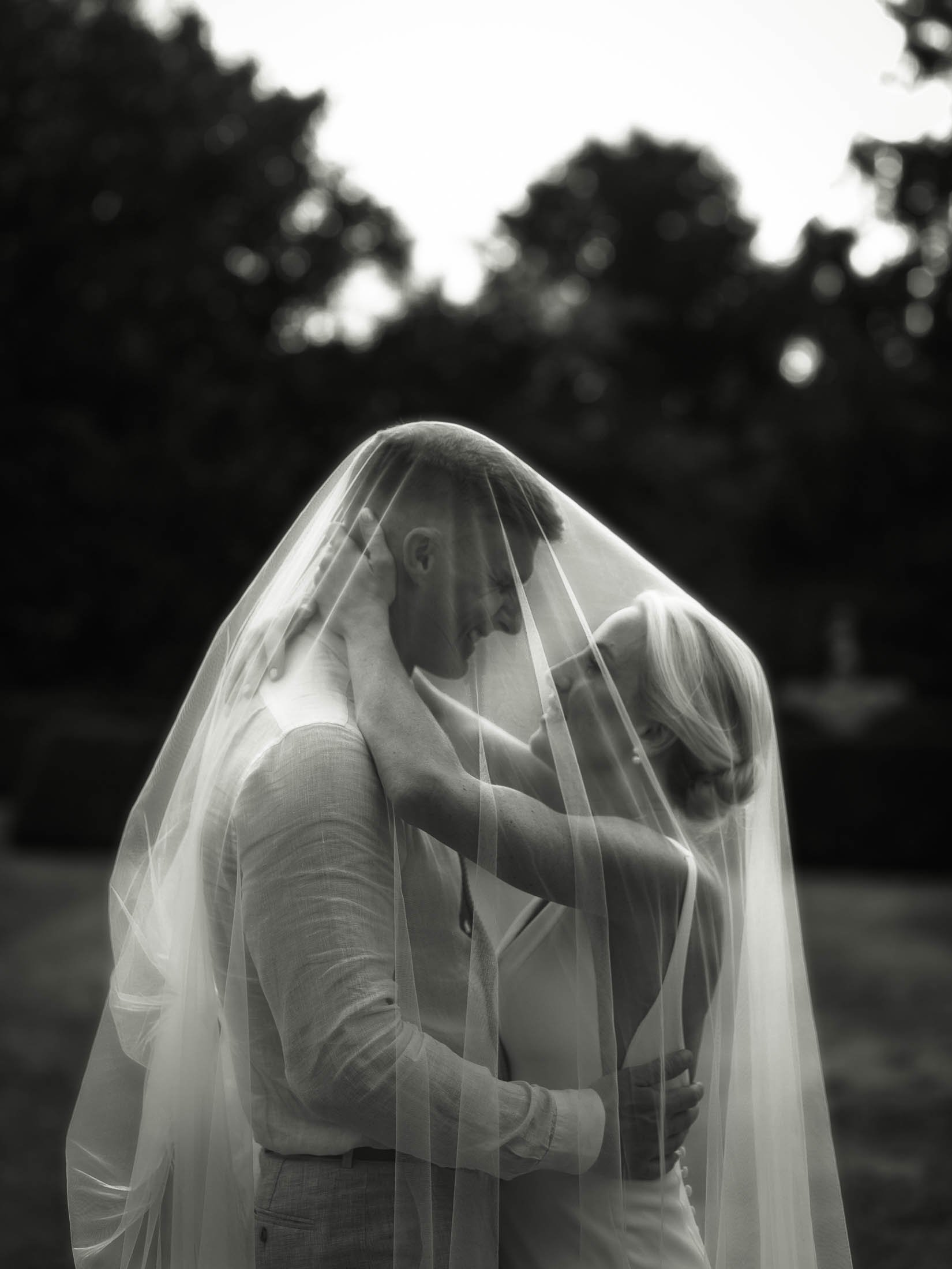 An elegant and editorial black and white wedding photograph of a bride and groom underneath a veil, captured at the Winters Barns wedding venue in Kent.