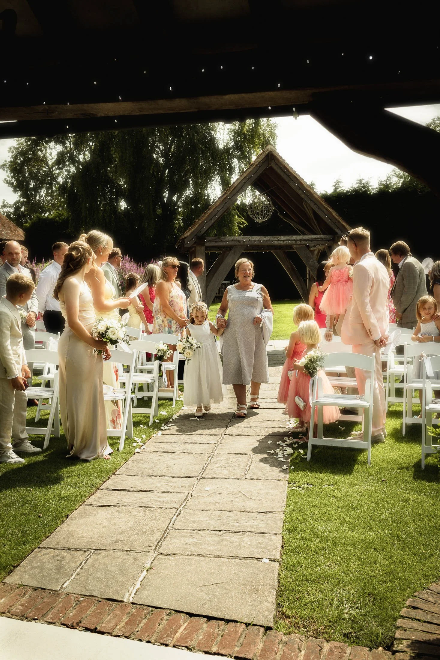 An outdoor summer wedding ceremony moment as the Mother of the Bride and daughter of the Bride walk down the aisle together at Winters Barns.