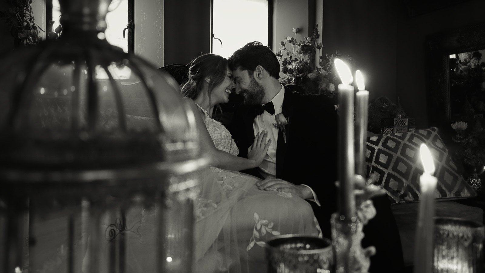 Black and white fine-art image of a bride and groom smiling during their wedding breakfast.