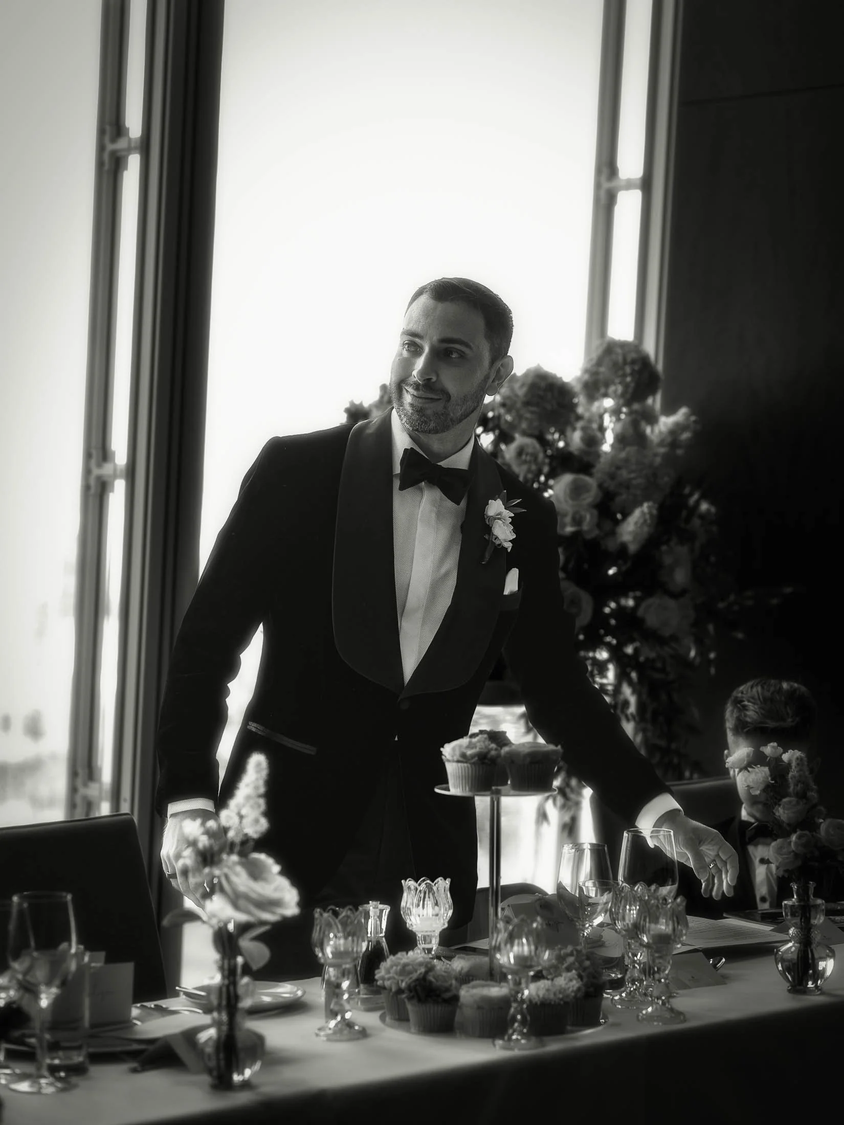 A groom in black tie stands up and delivers a speech to his bride and guests during a formal London wedding at the Shangri-La hotel at The Shard.