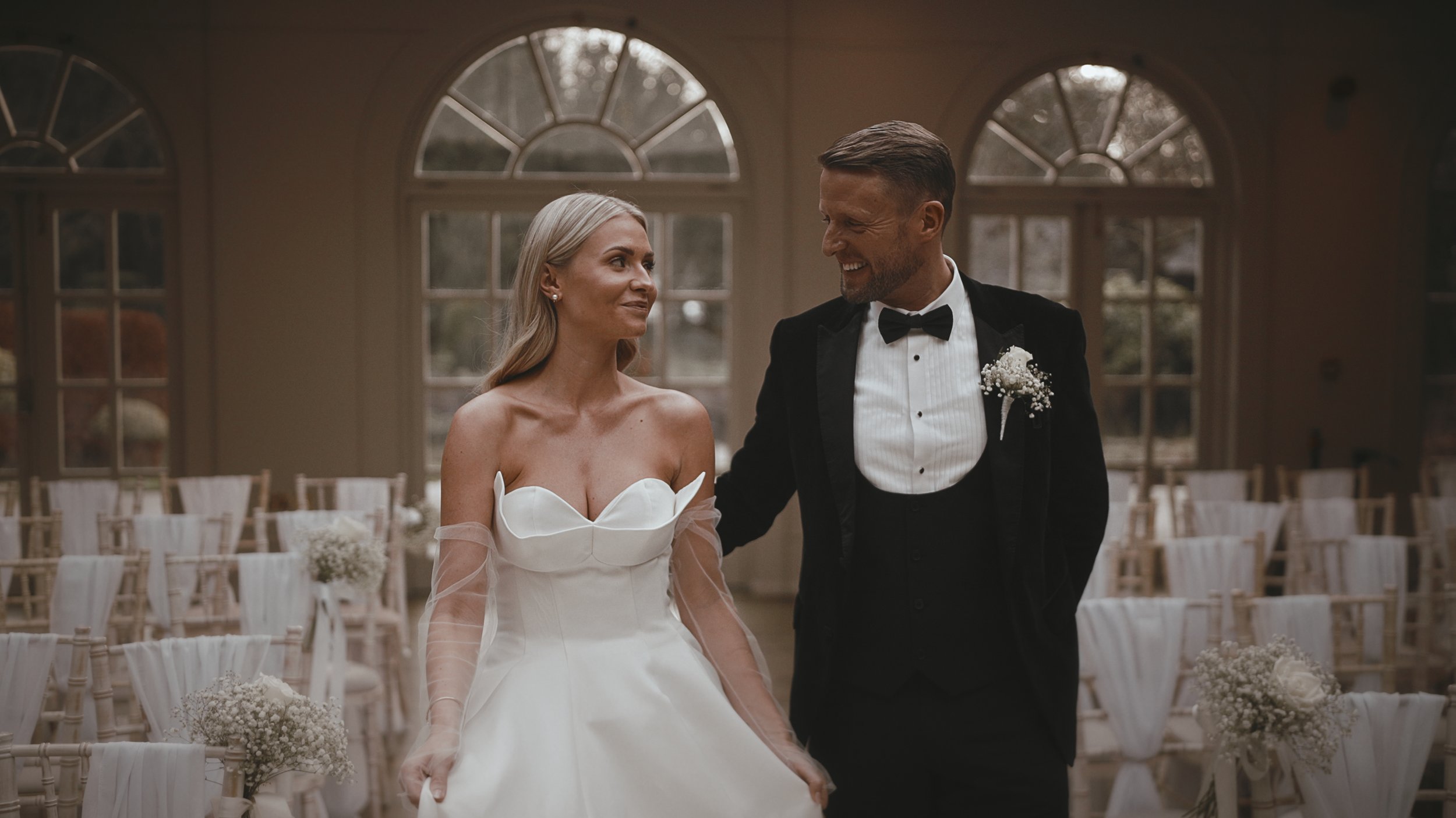 A couple walk through their black tie wedding during their fine art storytelling wedding film in the UK.
