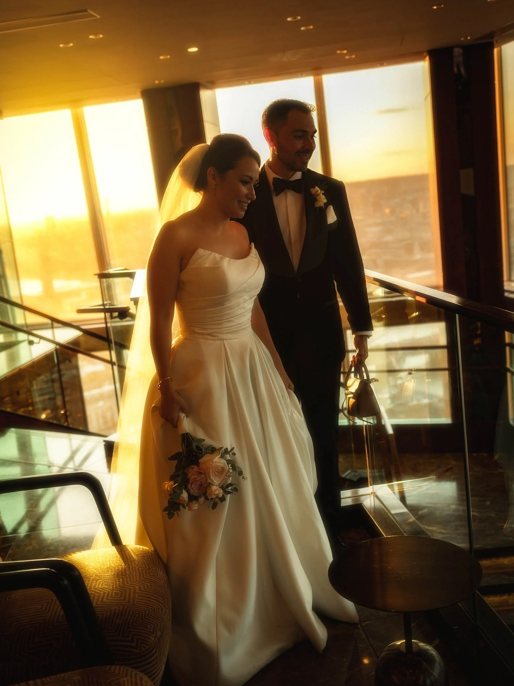 A bride and groom look down on their wedding reception at the Shangri-La hotel in the Shard as the sun sets across the London skyline behind them.