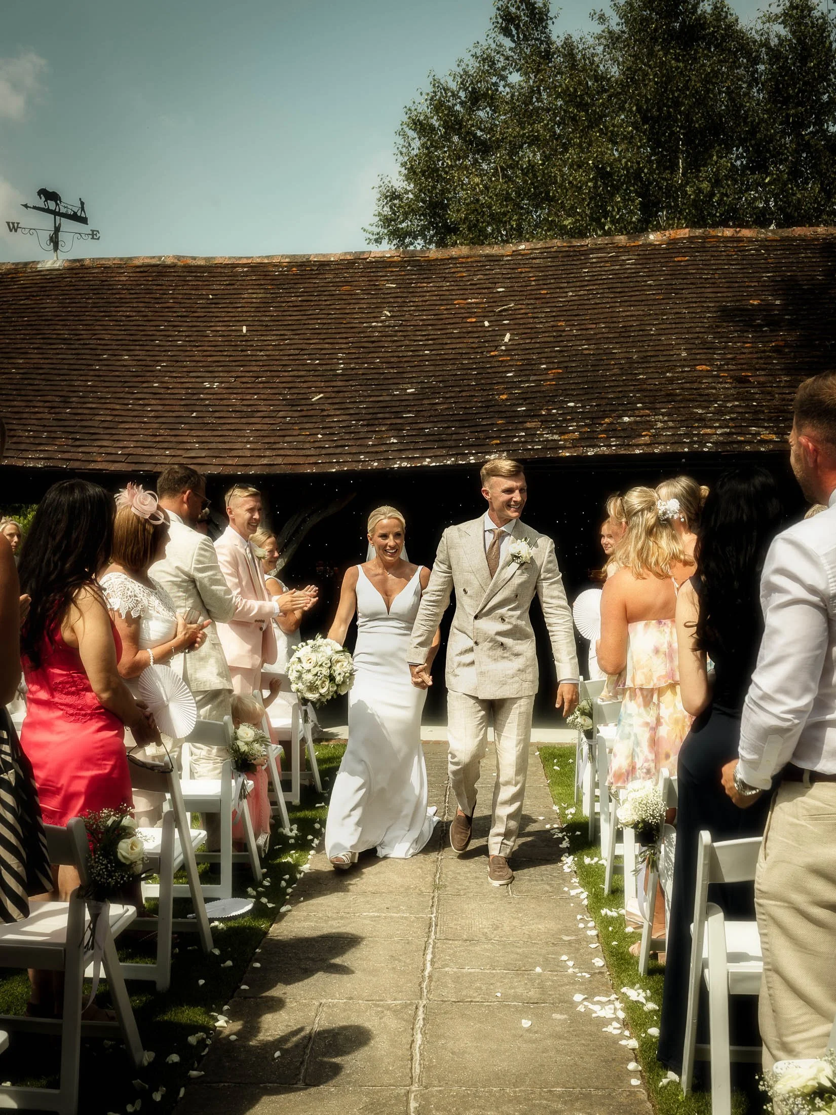 The bride and groom exiting their outdoor summer wedding ceremony at Winters Barns in Canterbury, Kent.