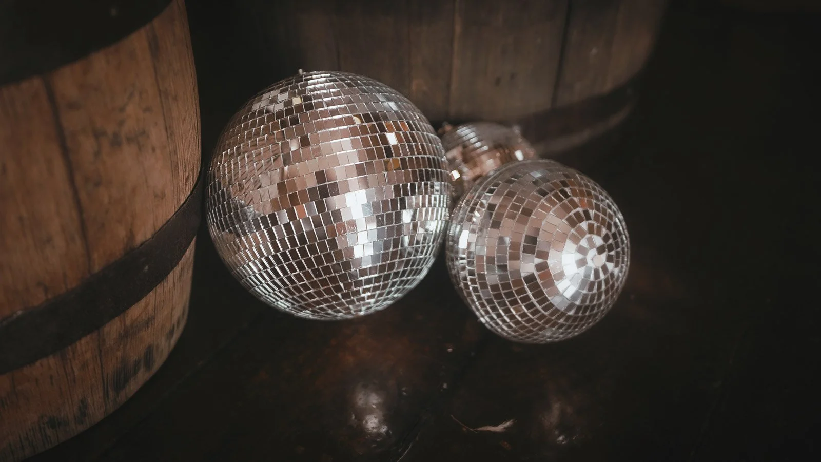 Glitter balls and wooden barrels acting as wedding decor in the main barn of Winters Barns, Kent.