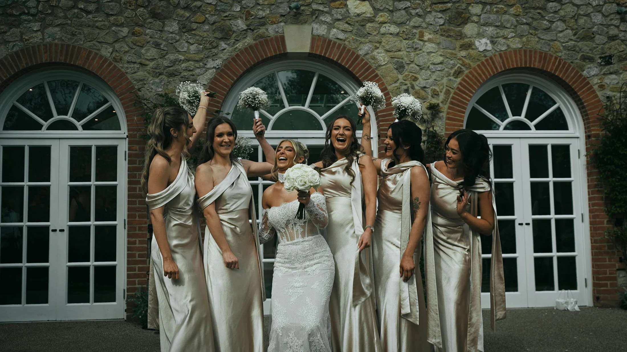 A bride laughs with her bridesmaids during group shots at The Orangery Maidstone wedding venue in the UK.