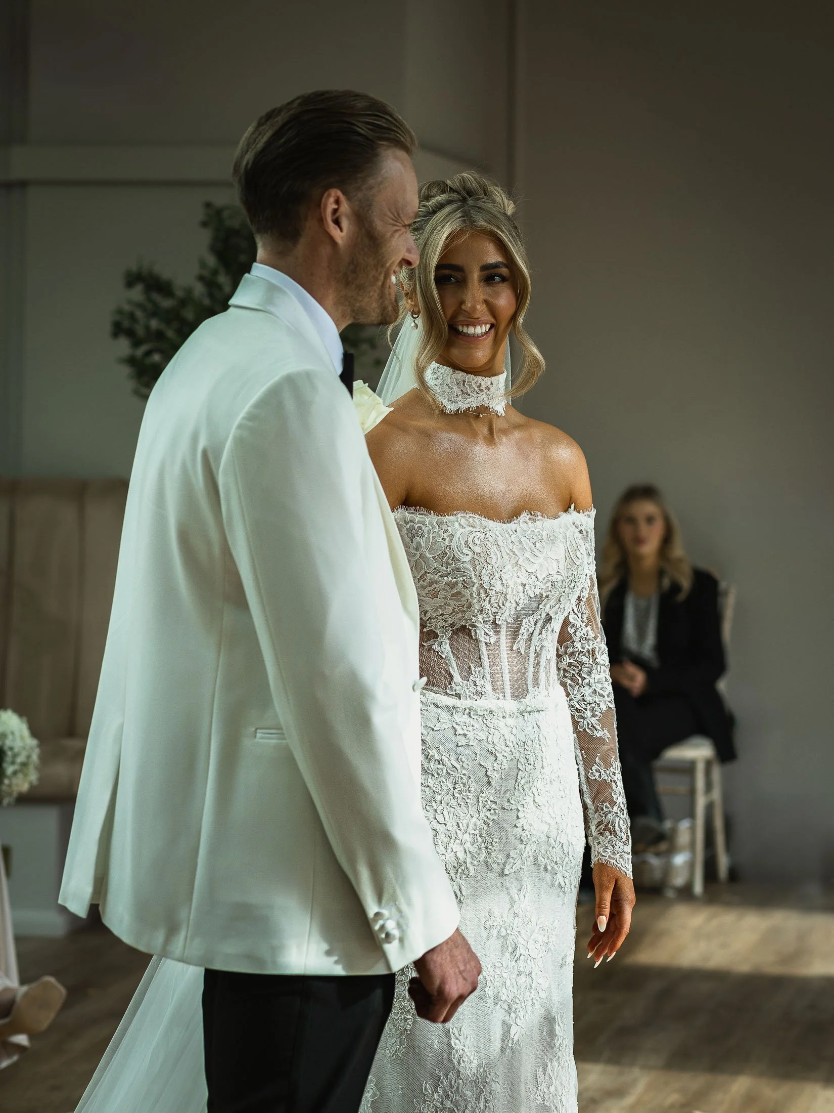 A bride smiles at her groom in the middle of their indoor wedding ceremony at the Orangery Maidstone.