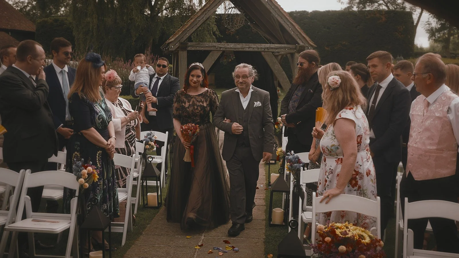 Bride walking down the outdoor ceremony aisle at Winters Barns surrounded by guests