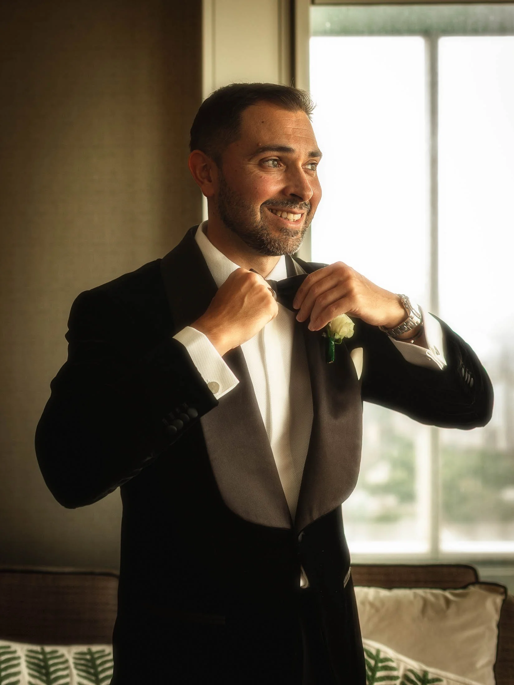 A groom in black tie adjusts his bow tie during morning preparations at the Shangri-La hotel at the Shard, London.