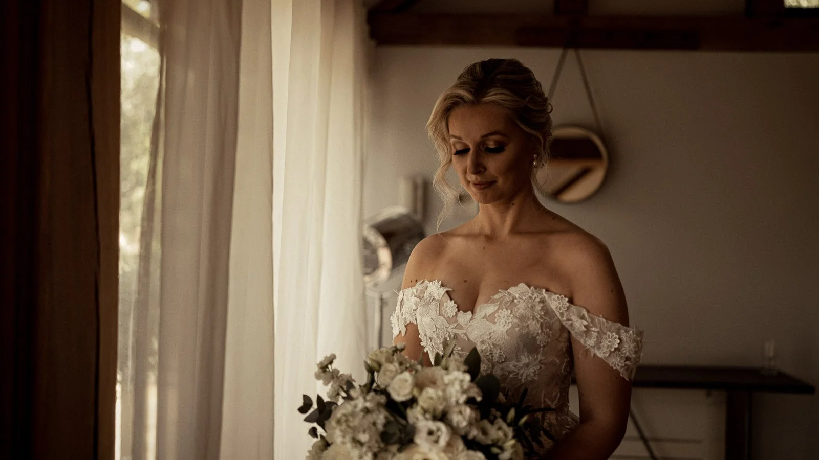 The bride looks down at her bouquet in an emotional moment during a Cooling Castle wedding film captured in Kent.