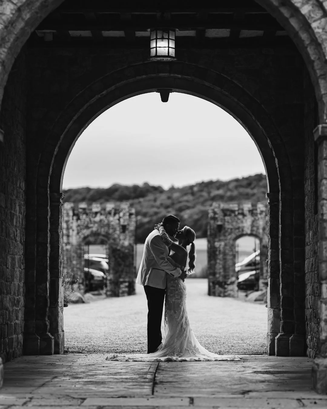 A creative wedding team capture photos and film of a couple underneath an archway at Eastwell Manor in Kent