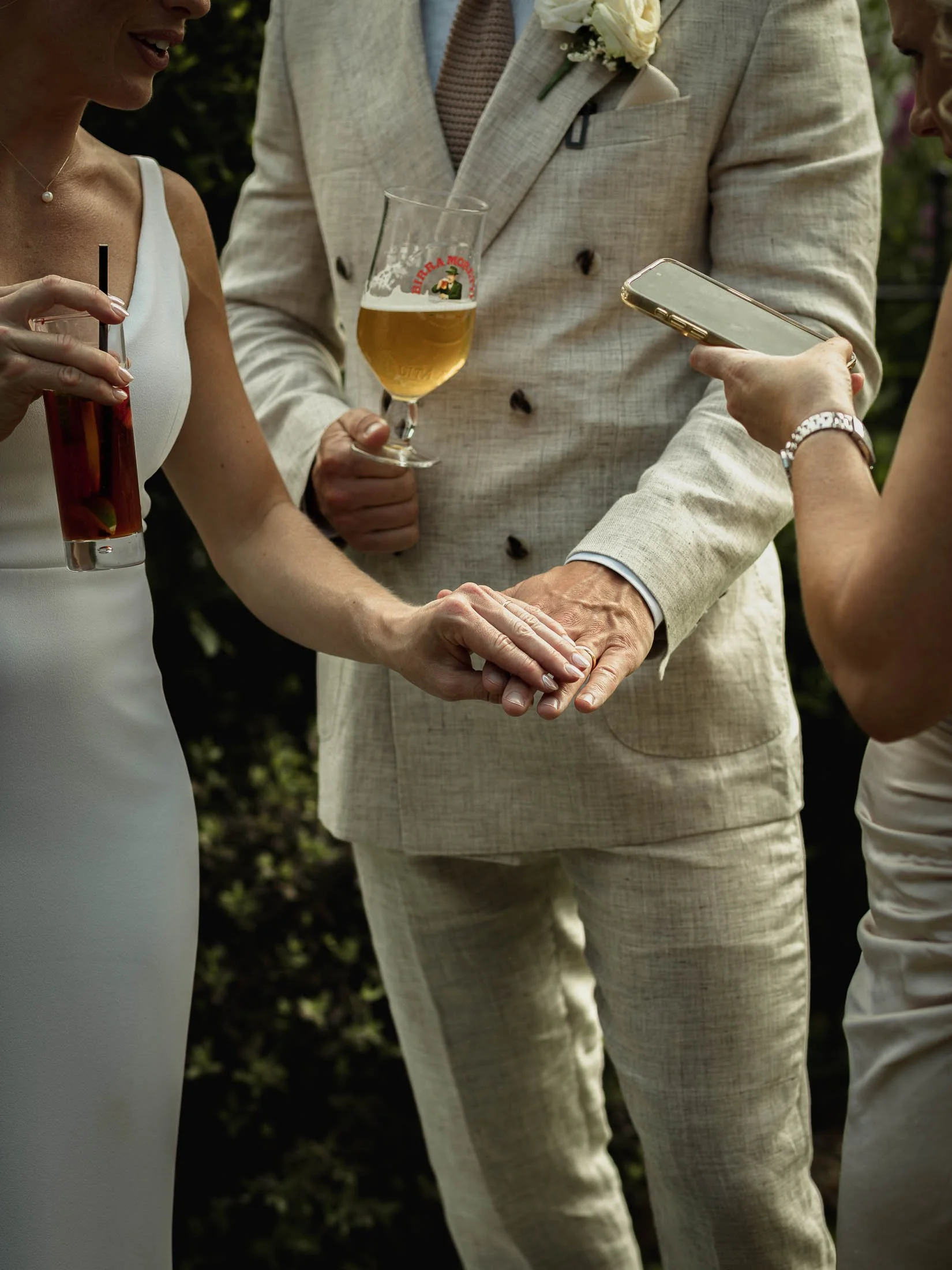 A close-up wedding photograph of the bride and grooms hands together, showing their wedding rings.