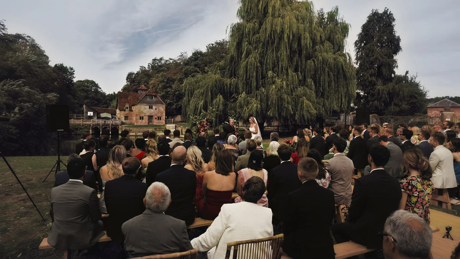 A bride and groom laughing during their colourful riverside wedding ceremony on the banks of the River Thames.
