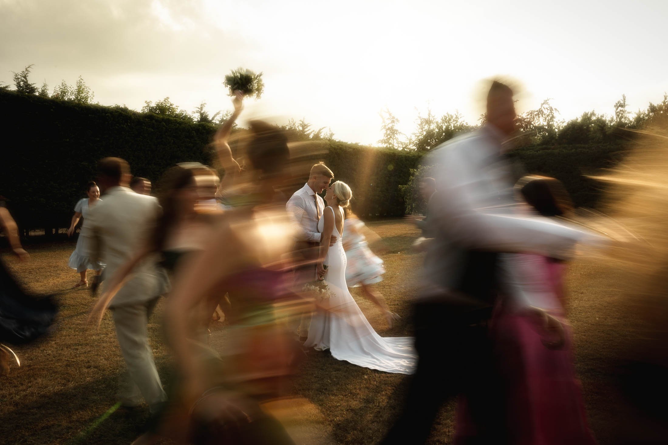 A creative wedding photography and videography shot using a shutter drag effect, as the bridal party run around the bride and groom at Winters Barns.