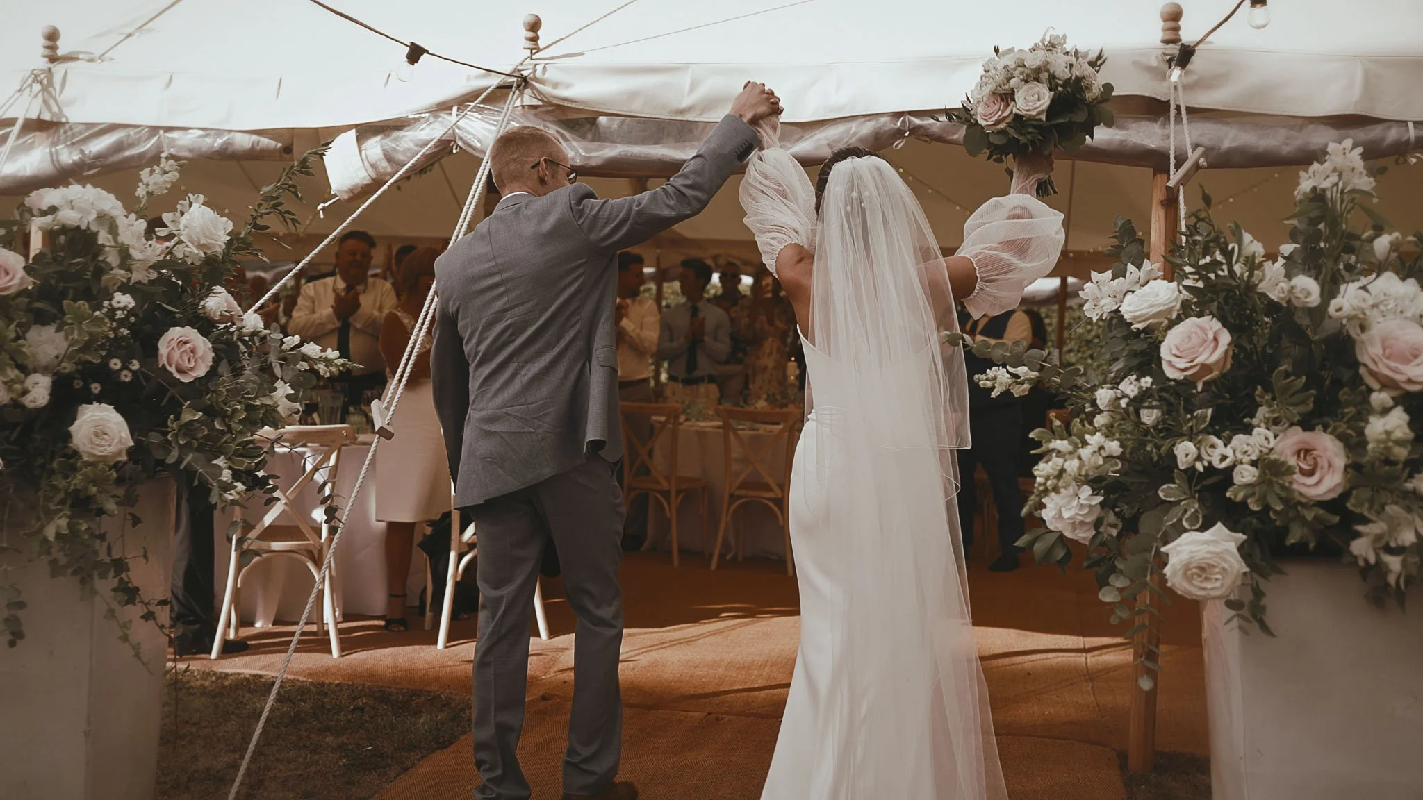 A bride and groom cheer as they enter their luxury marquee during their destination wedding in Europe.