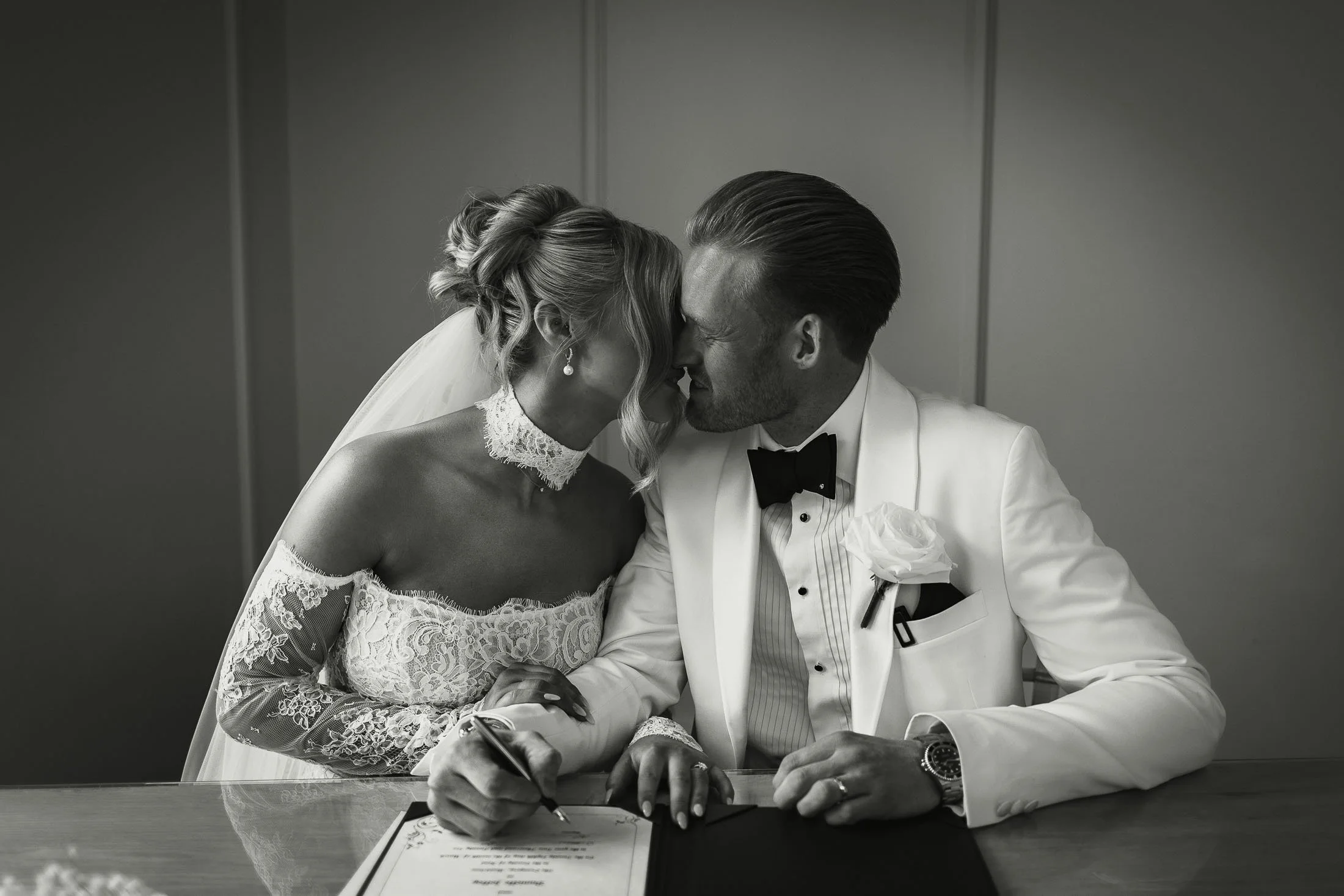 Black and white editorial wedding photo of a bride and groom sharing a kiss during their indoor wedding ceremony at The Orangery Maidstone.
