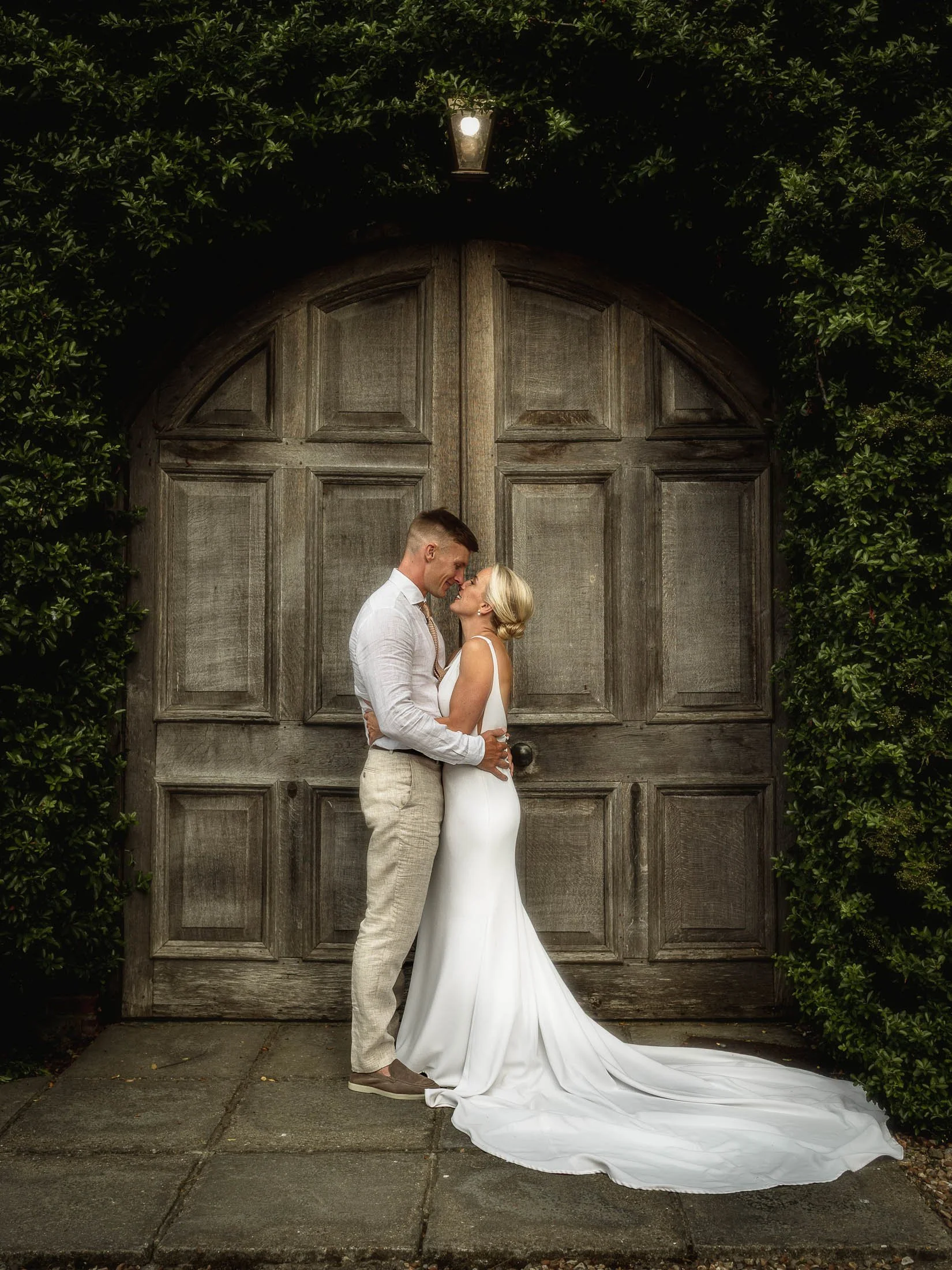 A couple stand intimately together by the famous barn doors at Winters Barns wedding venue in Kent, captured by both wedding photography and videography as part of a cohesive team approach.