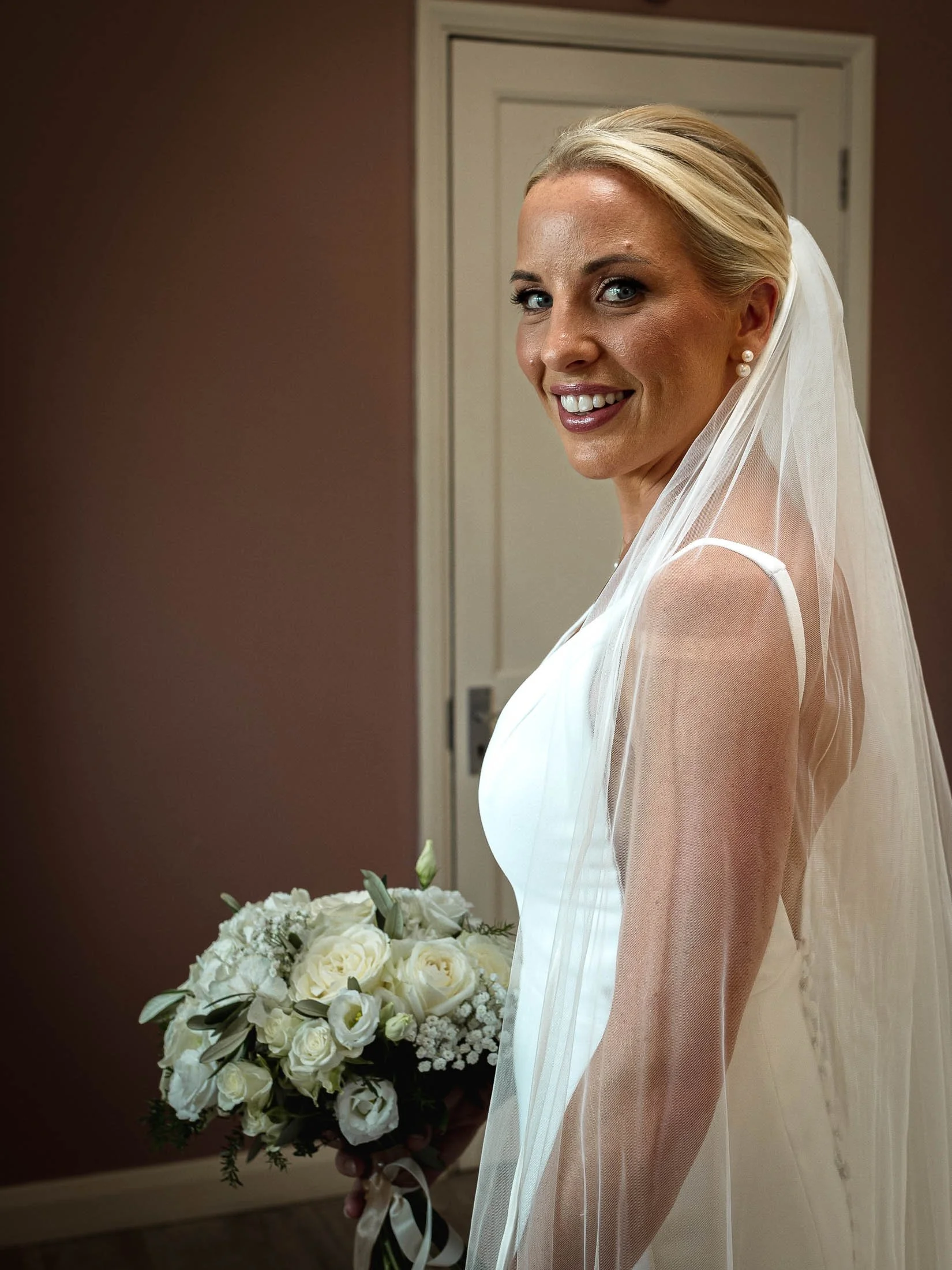 A relaxed bridal portrait in the bridal preparation suite at Winters Barns wedding venue in Kent, with the bride smiling and looking directly at the lens.