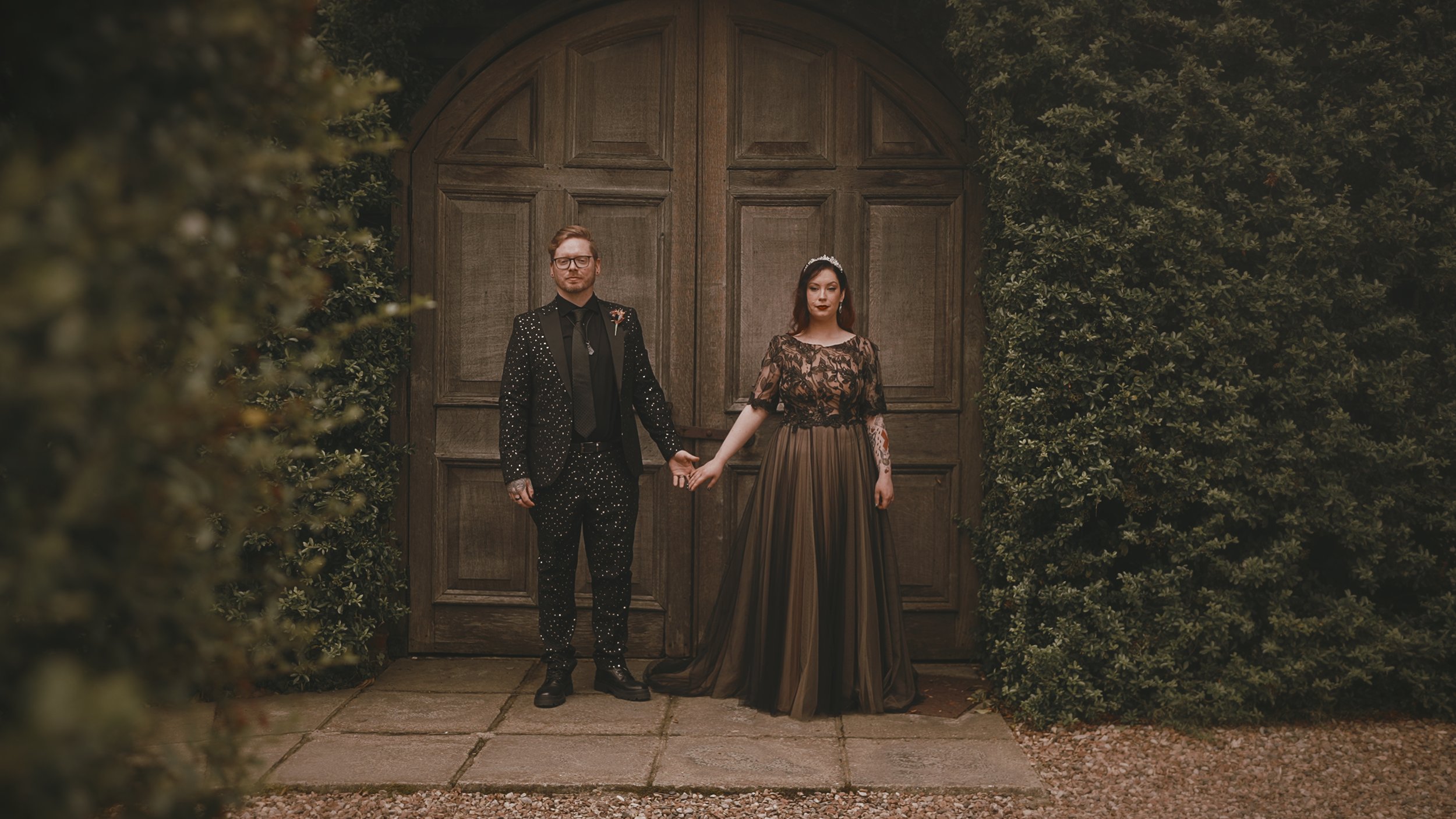 Cinematic wedding portrait of an alternative bride and groom by the barn doors at Winters Barns in Kent, captured in an editorial, fine art style.