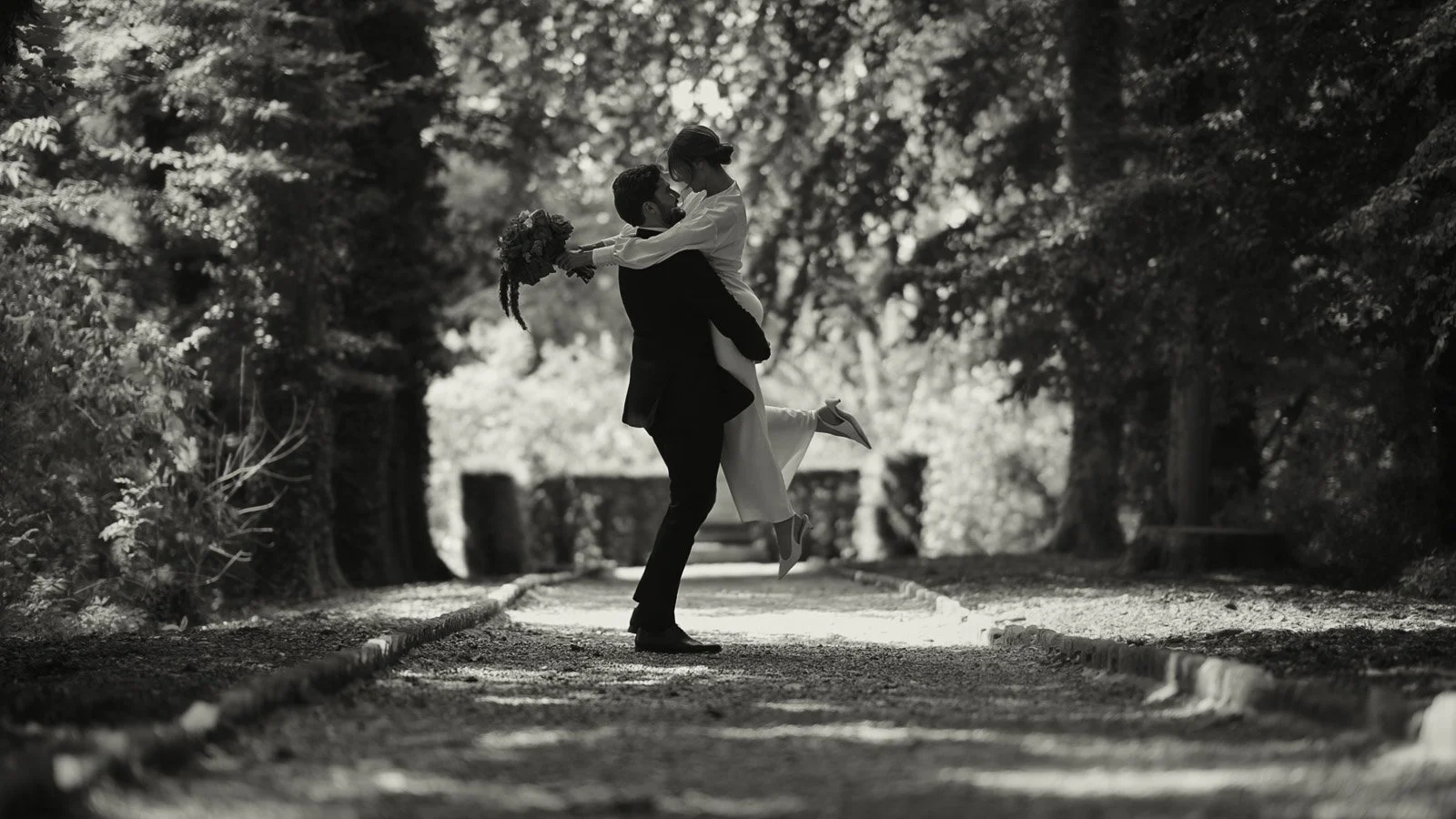 A groom picks up and spins his bride in a black and white editorial moment at a black tie wedding.