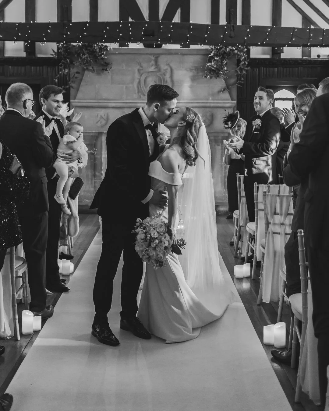 An indoor wedding ceremony is captured by a professional photography and videography team.