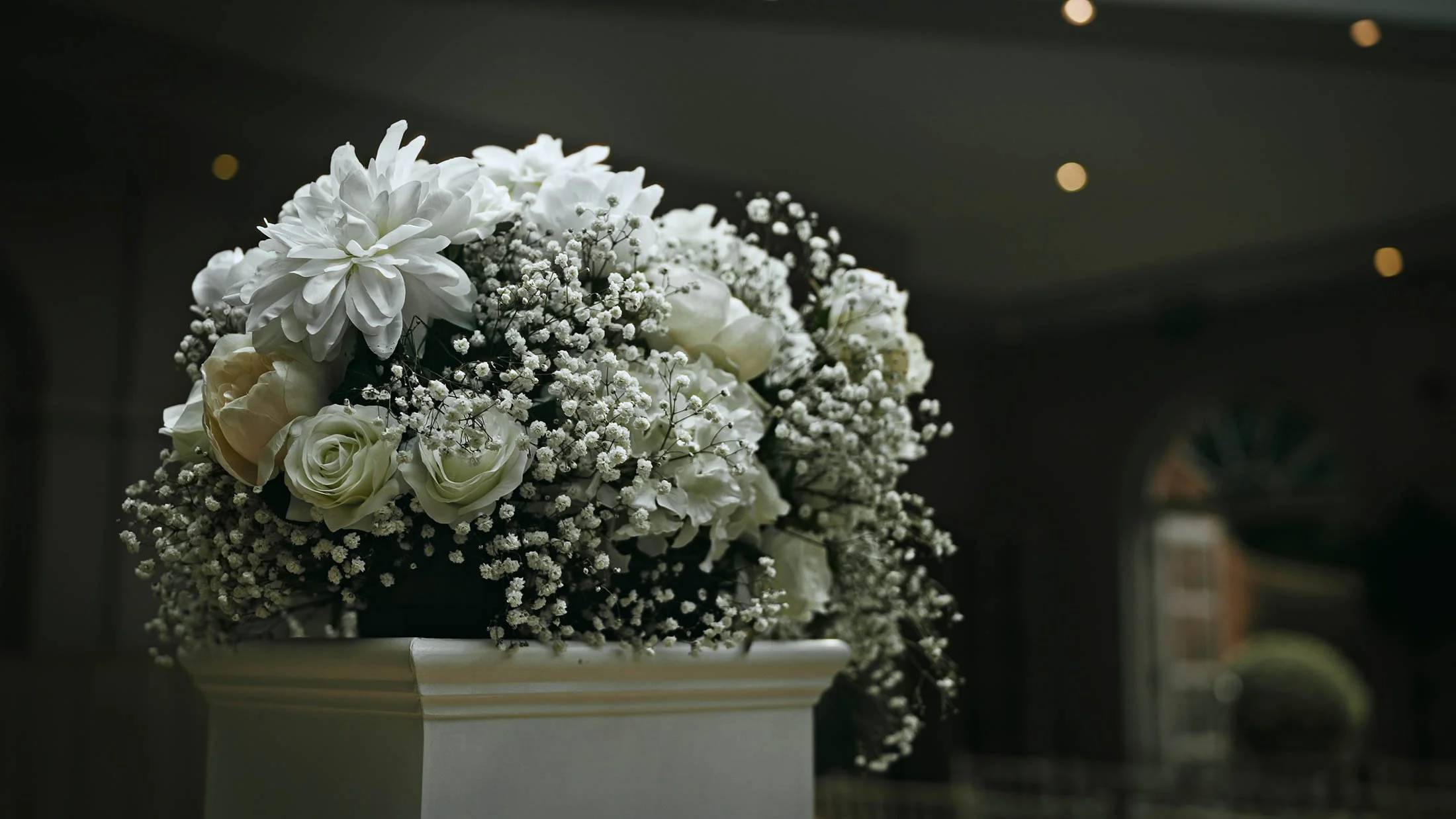 Flowers stand in a podium during an indoor wedding ceremony.