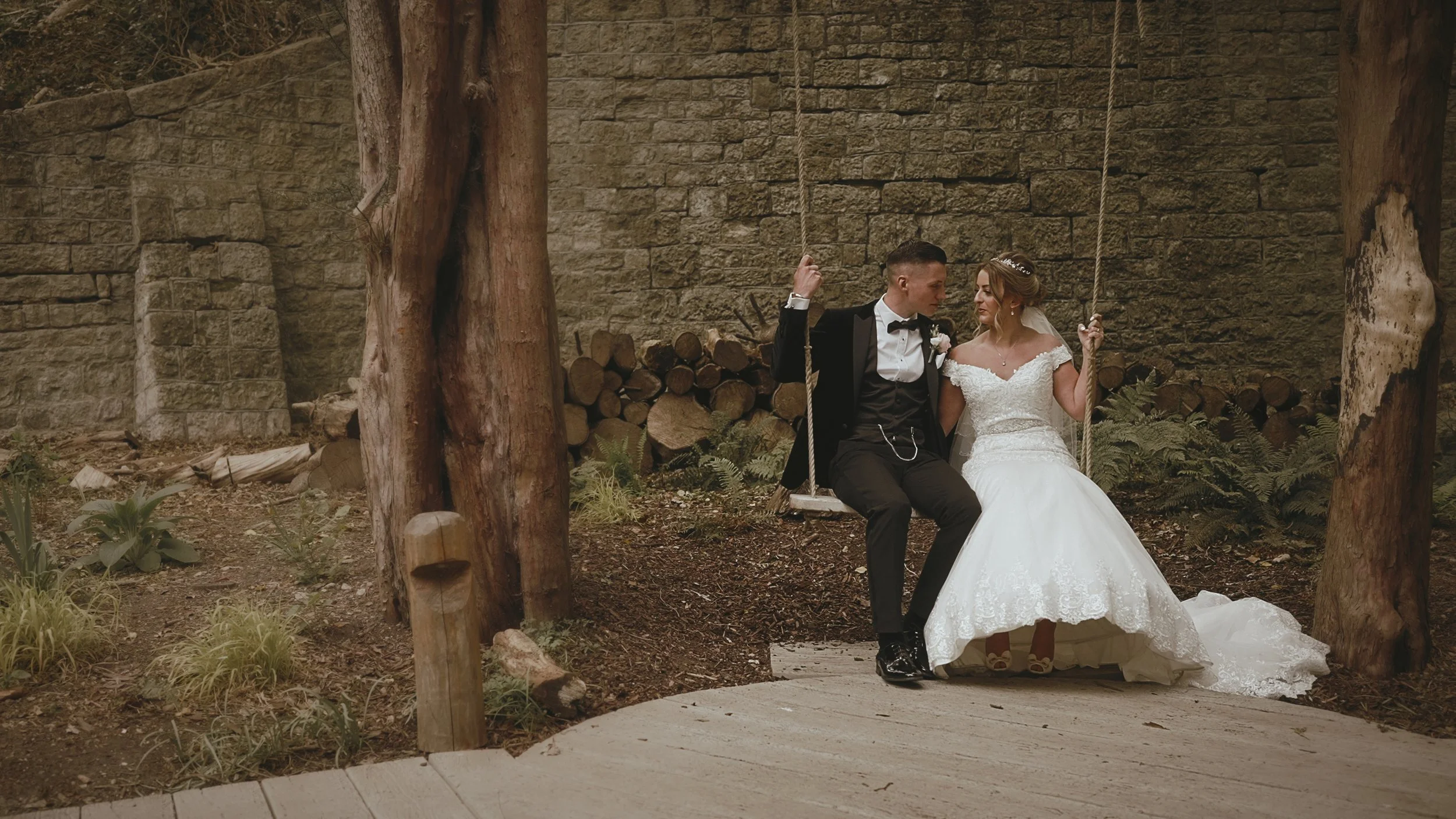 A couple sit on a swing in the grounds of The orangery Maidstone during their Black tie wedding at the Orangery in Kent