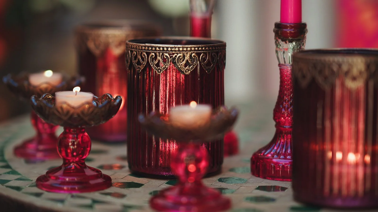 Glass jars and candle holders with gold detailing and pink colours decorate a fashion-forward wedding reception.