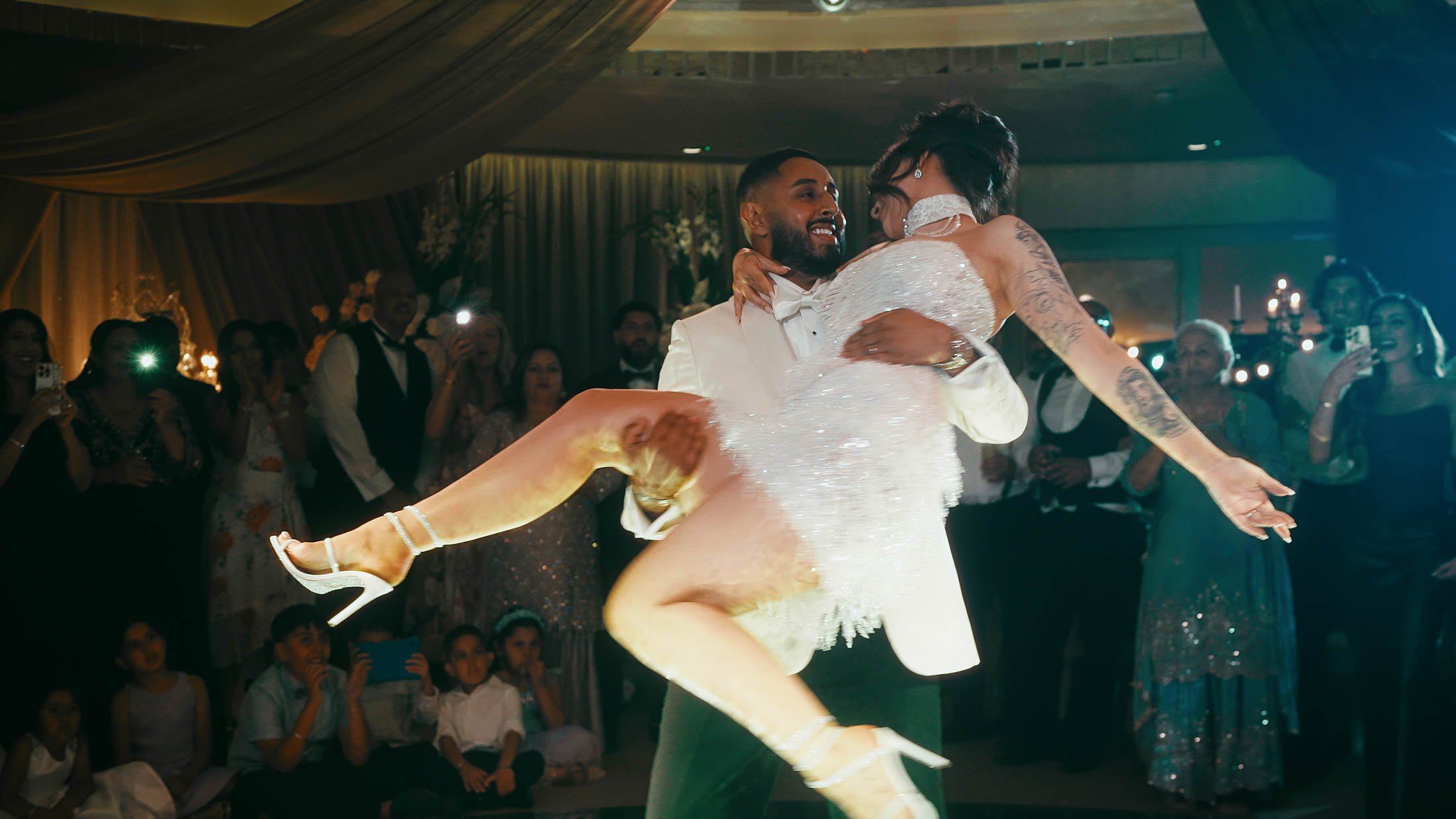 A groom picks up his bride and spins her around during their first dance in the Grantley Suite at their Grantley Hall wedding in Yorkshire.